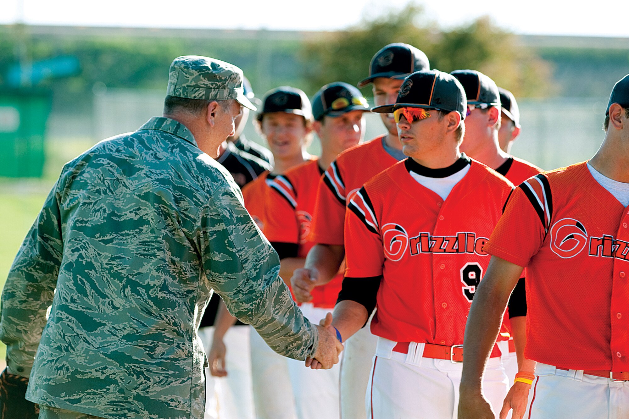 Col. Greg Tims, 90th Missile Wing commander, shakes hands with Tyler Stevenson, No. 9, before the game on June 24. (U.S. Air Force photo by Jeff Allred)