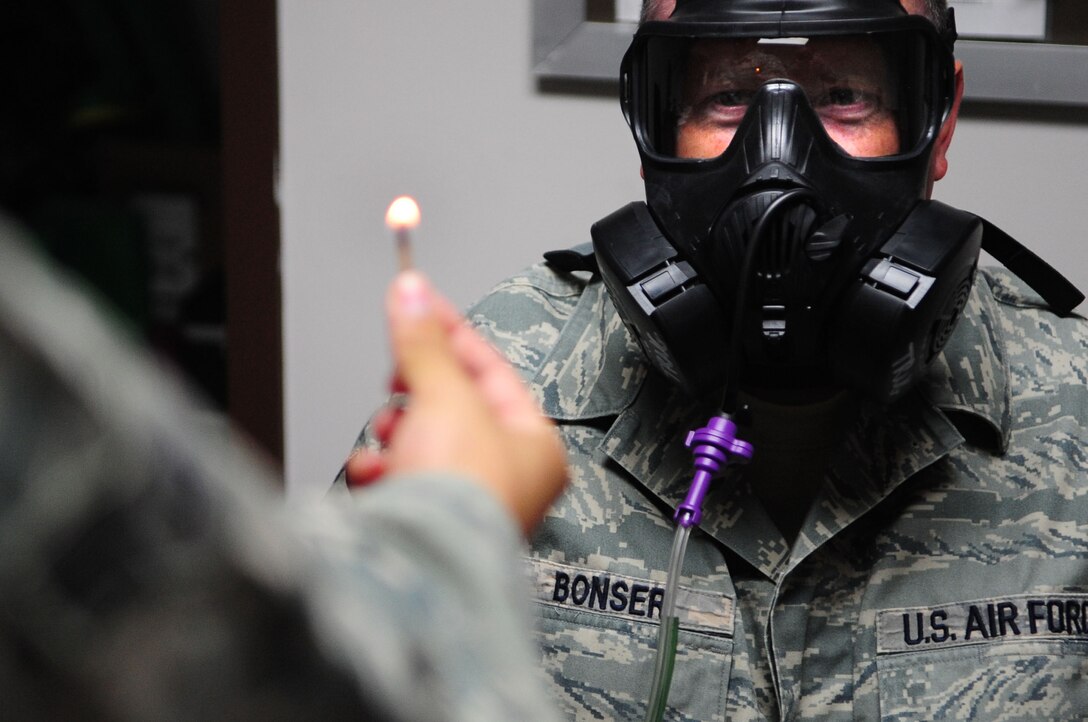ELLSWORTH AIR FORCE BASE, S.D. – Airman 1st Class Larry Pedraza, 28th Medical Group bioenvironmental engineering apprentice, lights a match to create particles during a gas mask fit test on Master Sgt. Loren Bonser, 28th Bomb Wing public affairs superintendent, July 7. A gas detector is connected to the gas mask which reads the excess particles in the air to determine the effectiveness of the mask. The air inside the mask must be 2,000, or more, times cleaner than the air outside the mask. (U.S. Air Force Photo/Airman 1st Class Corey Hook)