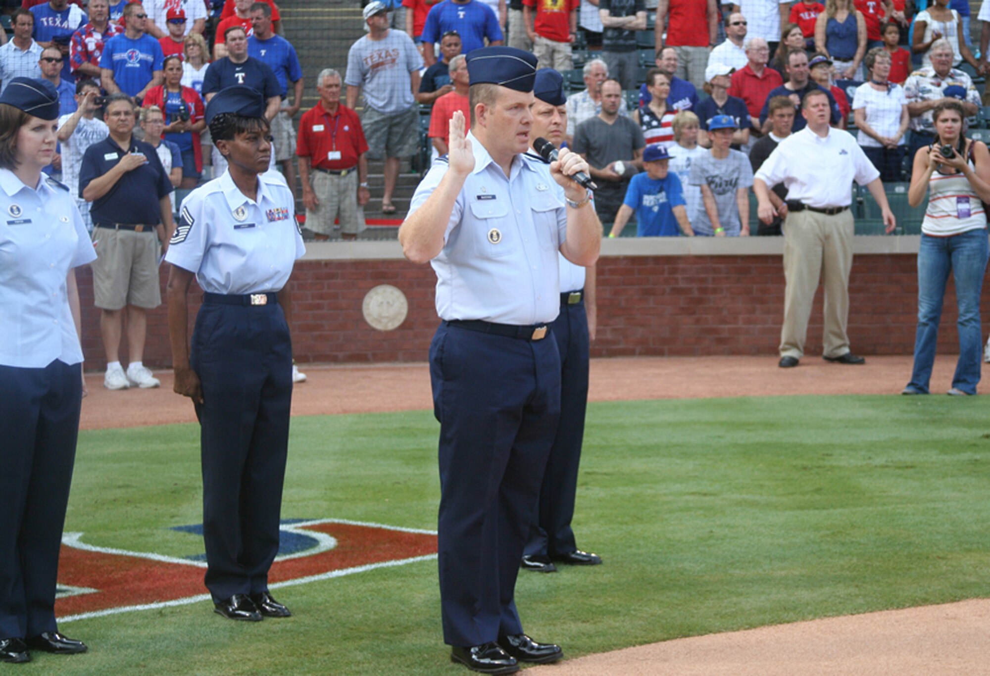 On July 4, 142 new Airmen from the 344th Recruiting Squadron’s Delayed Entry Program took the Oath of Enlistment before the Texas Rangers baseball game July 4 in Arlington, Texas. Lt. Col Sean McKenna, commander of the 344th RCS, administered the oath in front of more than 45,000 people. “Getting the chance to work with the Texas Rangers and put the Air Force front and center on the 4th of July is a wonderful opportunity," Colonel McKenna said. “The fans are always so supportive and the new recruits get a once-in-a-lifetime chance to be in the spotlight on one of our nation’s most significant days.”  Pre-game festivities included 12 Air Force recruiters holding the U.S. Flag in the outfield, two Air Force mini-jet airplanes on the ground and a formation of Air Force F-16s performing a fly-over. (U.S. Air Force photo/Tech. Sgt. Dustin Beard)