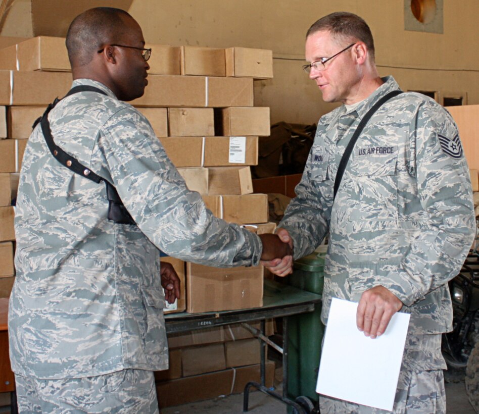 Lt. Col. Kenneth Evans, 577th Expeditionary Prime Base Engineer Emergency Force Squadron commander, presents Tech. Sgt. Steven Wolf with a coin during a commander's call at Bagram Airfield, Afghanistan, July 3. Sergeant Wolf is a pavement construction and equipment operator specialist with the 577th EPBS and is deployed from the 434th Civil Engineer Squadron at Grissom Air Reserve Base, Ind. Coins are often presented to troops by military leaders to recognize outstanding performance. (U.S. Air Force photos/Staff Sgt. Elisabeth Floyd)