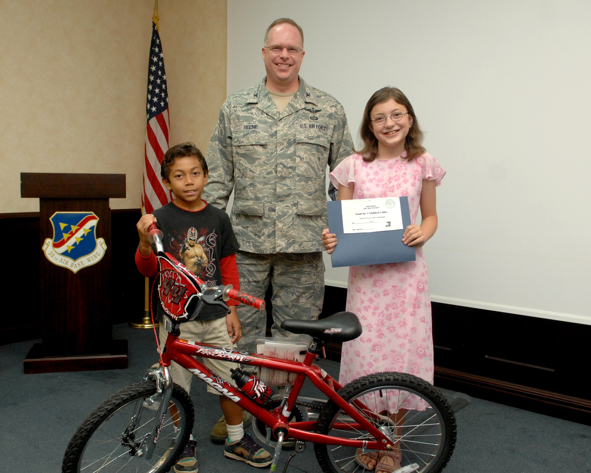 Bicycle Safety Rodeo raffle winners Tyree Williams (left) and McKenna Gameros accept prizes from Col. Eric Beene, 39th Air Base Wing Commander, Tuesday, July 6, 2010 at Incirlik Air Base, Turkey.  Williams won a bike and Gameros won a gift certificate at the safety office sponsored rodeo.  The rodeo was about educating the community on bicycle safety.  With the help of volunteers, more than thirty bicycles received light maintenance, and an obstacle course was set up for younger riders.  (U.S. Air Force Photo/Tech. Sgt. Valda Wilson)