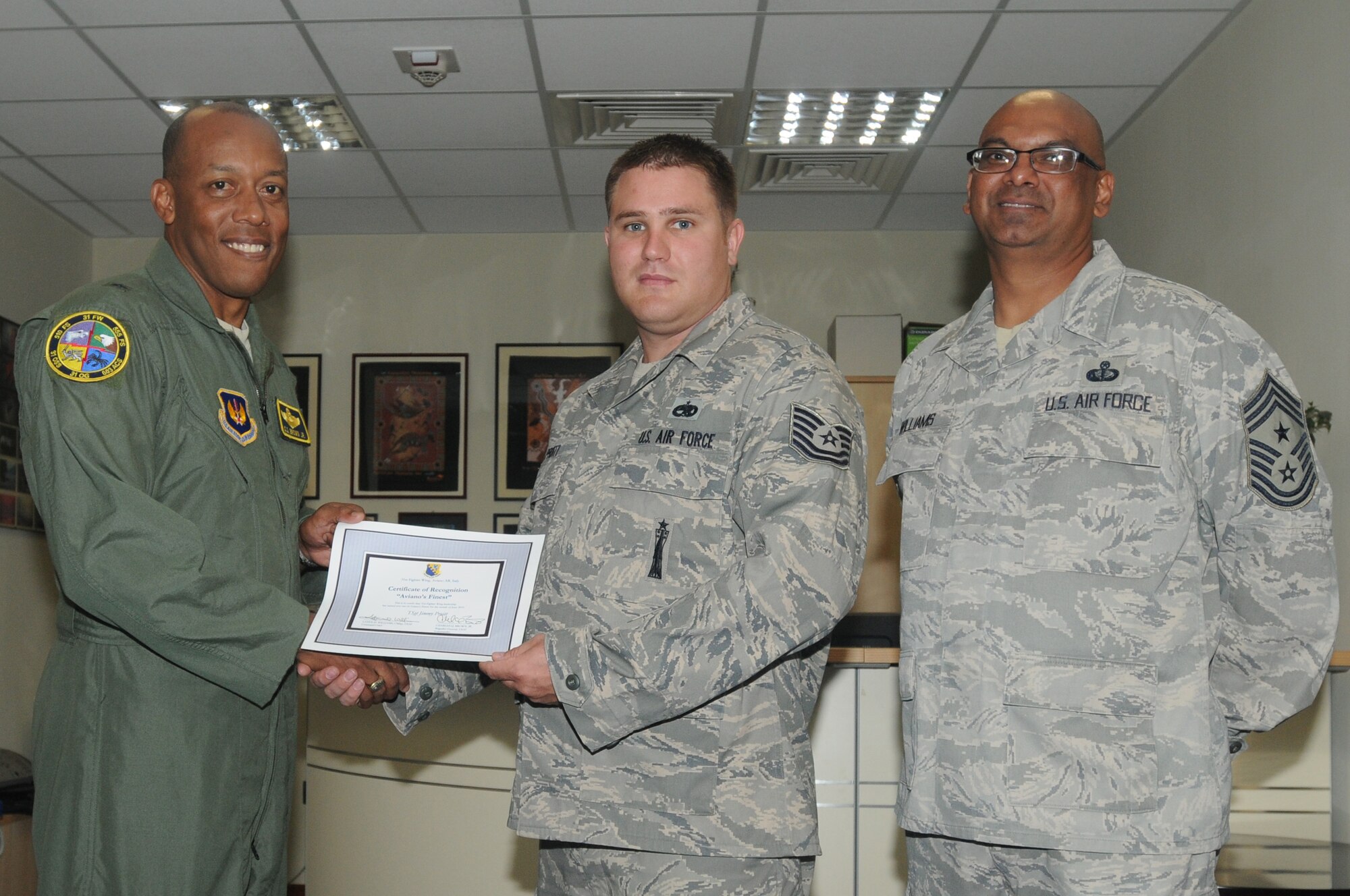 Brig. Gen. C.Q. Brown Jr., 31st Fighter Wing commander, congratulates Tech Sgt. Jimmy Pruitt, 31st Maintenance Operation Squadron Lead Standardization Crew Member, on his selection as one of Aviano's Finest as Chief Master Sgt. Laten Williams, 31st FW command chief, looks on.