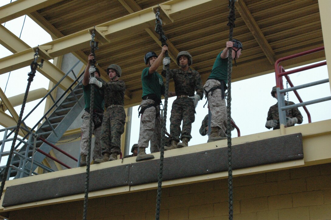 Company H recruits begin the steps of fast roping by repeating and doing what the Instructional Training Company drill instructors say. Once they have done that, they push off the edge and slide to the bottom of the rope attached to the rappel tower here.