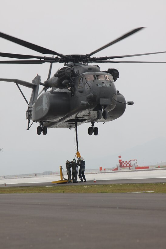 Sailors with Helicopter Mine Countermeasures Squadron 14 Detachment 1 out of Pohang, Korea, hook simulated cargo onto an MH-53E Sea Dragon during an external vertical replenishment exercise at the airfield here July 8. The training was held here due to the lack of resources in Pohang.