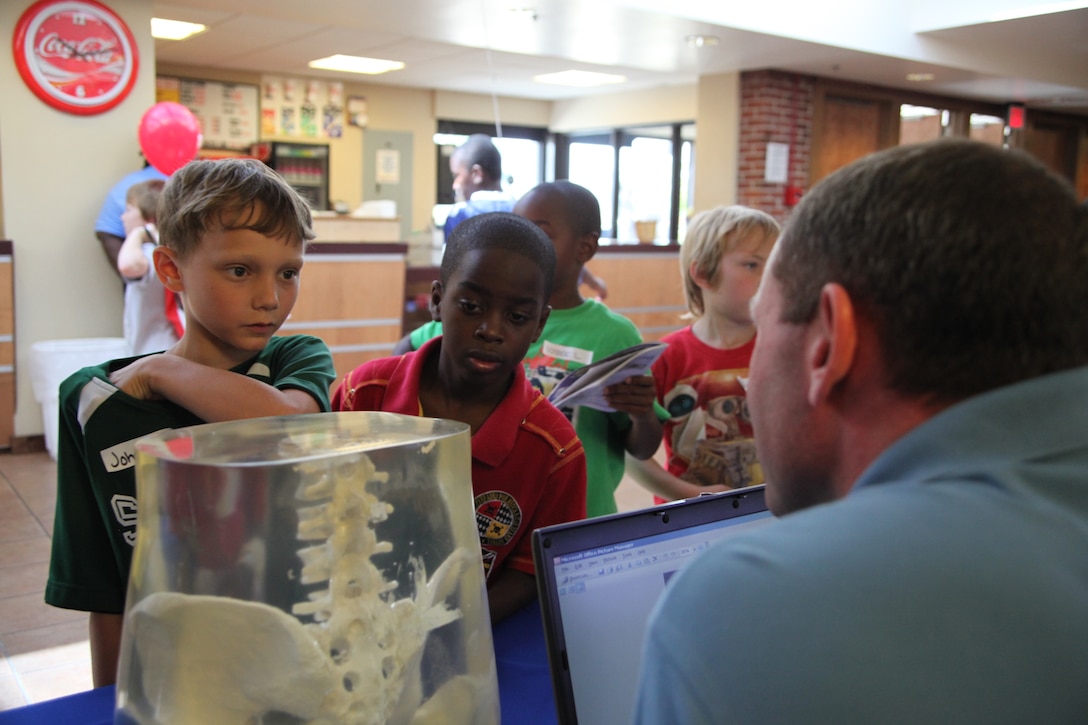 John Vaughan and Isiah McKeever, two Cherry Tree House campers, look into a diagram of a pelvic bone at the Kids Health and Fitness Fair at the air station theater, July 9. The annual event is to educate parents and their children about healthy eating and daily exercise.