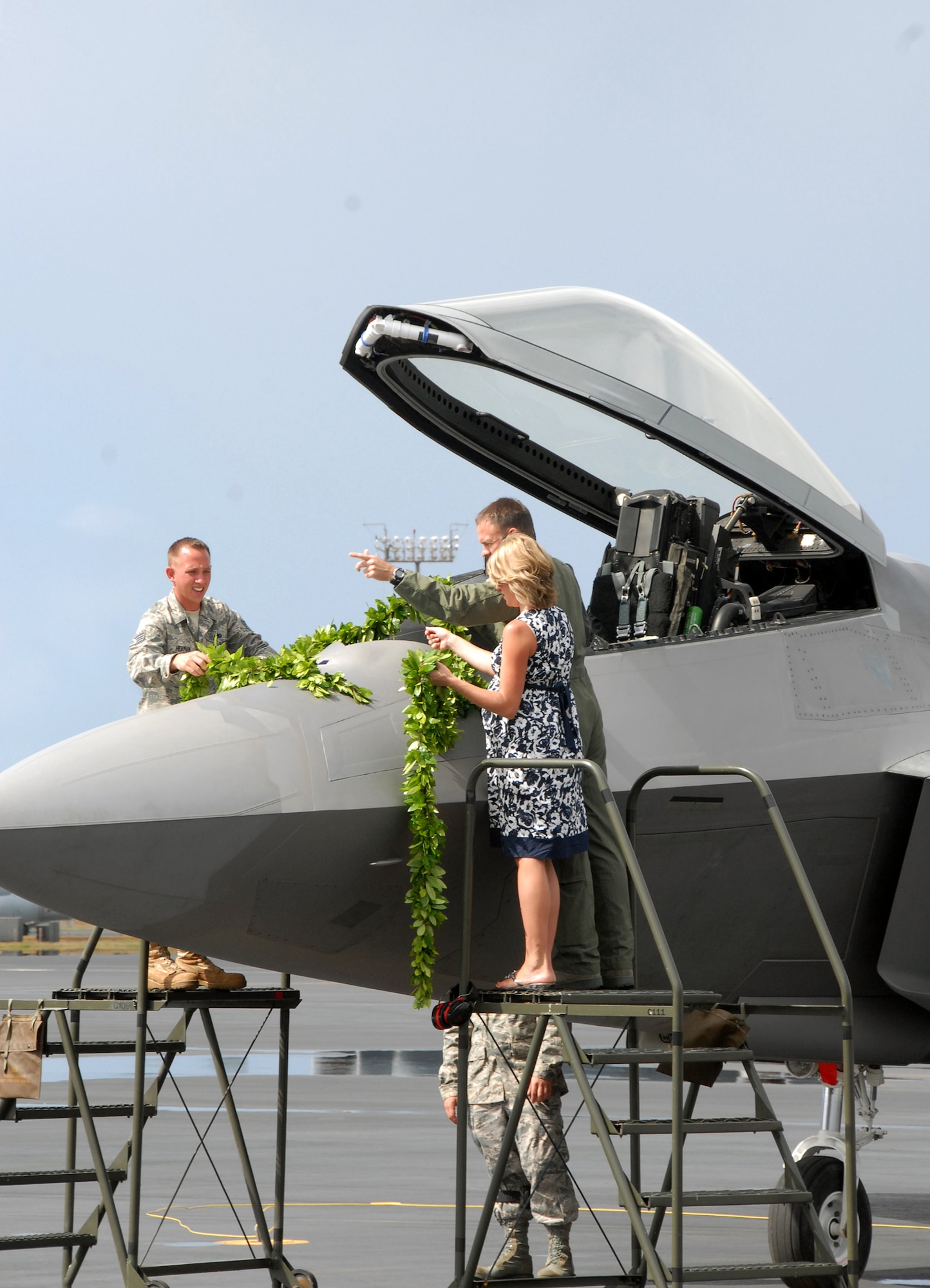 Lt. Col. Harvey "Banger" Newton, pilot 19th Fighter Squadron, along with his wife and Staff Sgt. Joel Herman, an active duty F-22 Raptor crew chief assigned to the 154th Wing Aircraft Maintenance Squadron, Hawaii Air National Guard, drape maile lei across the nose of the F-22 Raptor during the F-22 Arrival Ceremony July 9, on Joint Base Pearl Harbor-Hickam, Hawaii. Maile lei is part of a Hawaiian tradition used to mark important occasions. The arrival of the F-22 Raptor marks the beginning of a new associate unit between the Hawaii Air National Guard and the 15th Wing, active duty Air Force. (U.S. Air Force photo/Tech. Sgt. Betty J. Squatrito-Martin)