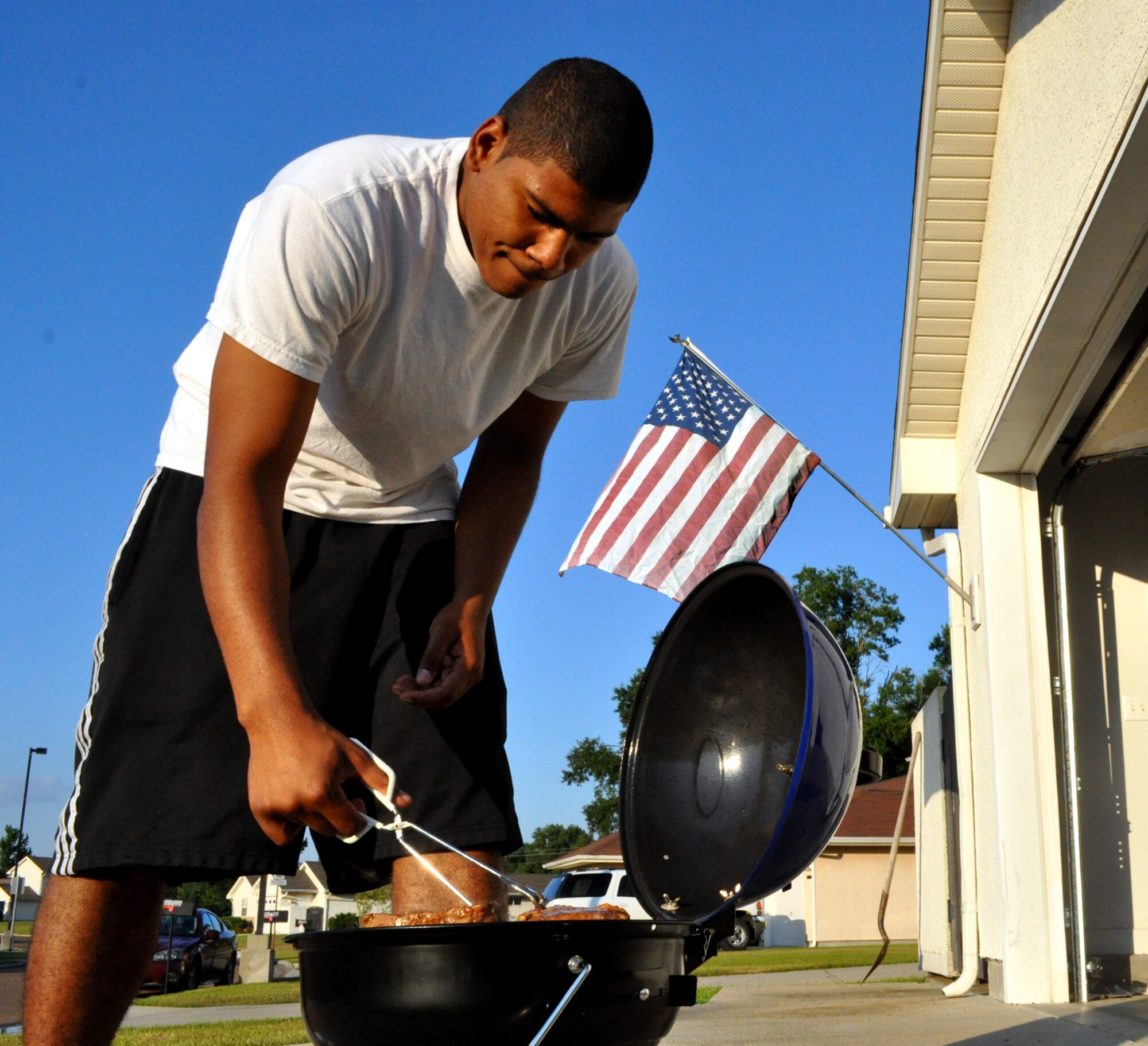 Senior Airman Marquis Skinner, a communications focal point technician with the 14th Communications Squadron, grills steaks in front of his home in here on base July 4. (U.S. Air Force photo/Airman 1st Class Chase Hedrick)