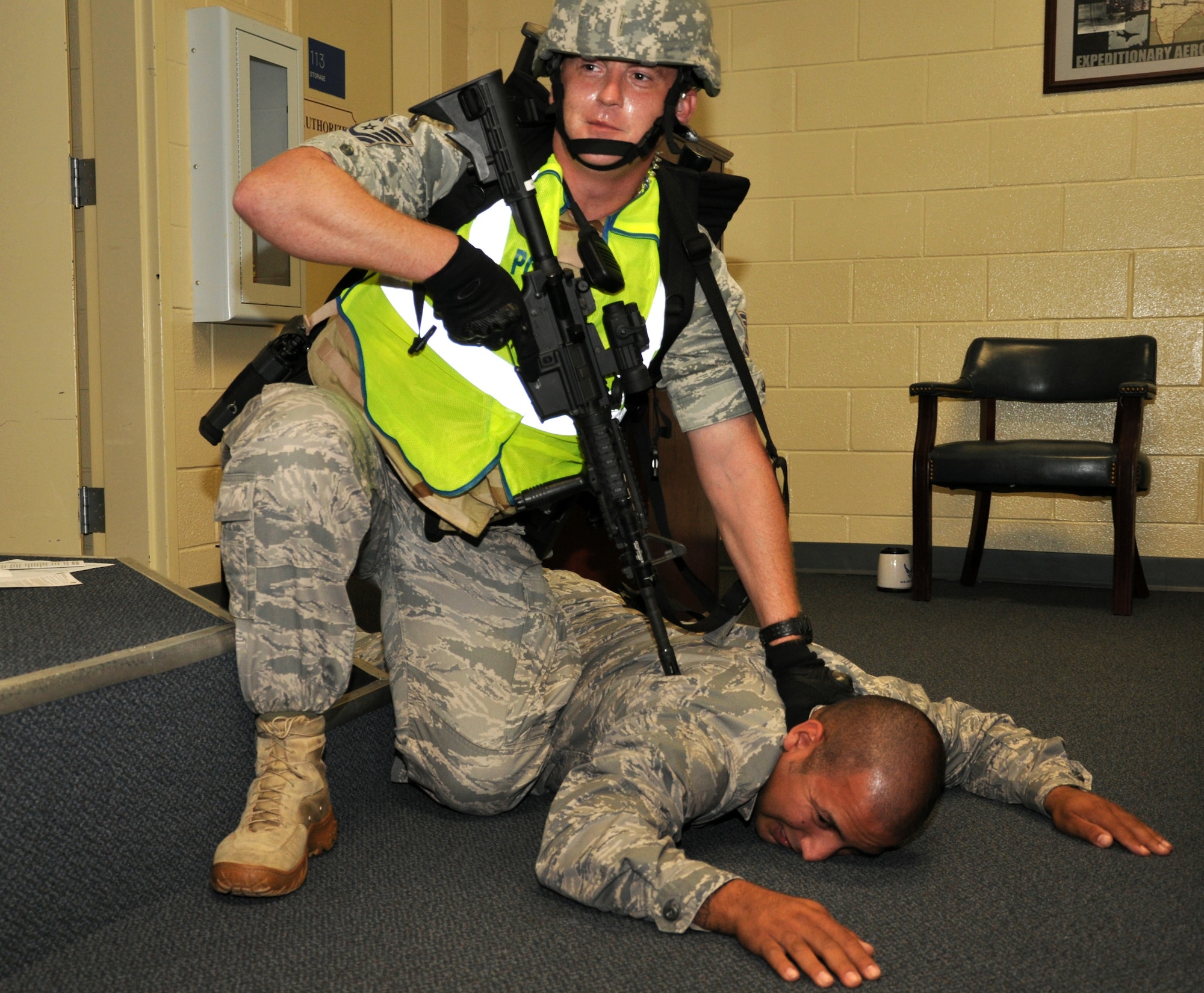 Tech. Sgt. Paul Ruhbusch pins Esteban Ruiz to the ground in effort to 'apprehend' him during a 96th Security Forces Squadron training event July 8. During the exercise squadron personnel responded to an 'active shooter' scenario where Mr. Ruiz, their instructor, played a military member who pulled out his 'gun' during a deployment briefing. (U.S. Air Force by Chrissy Cuttita)