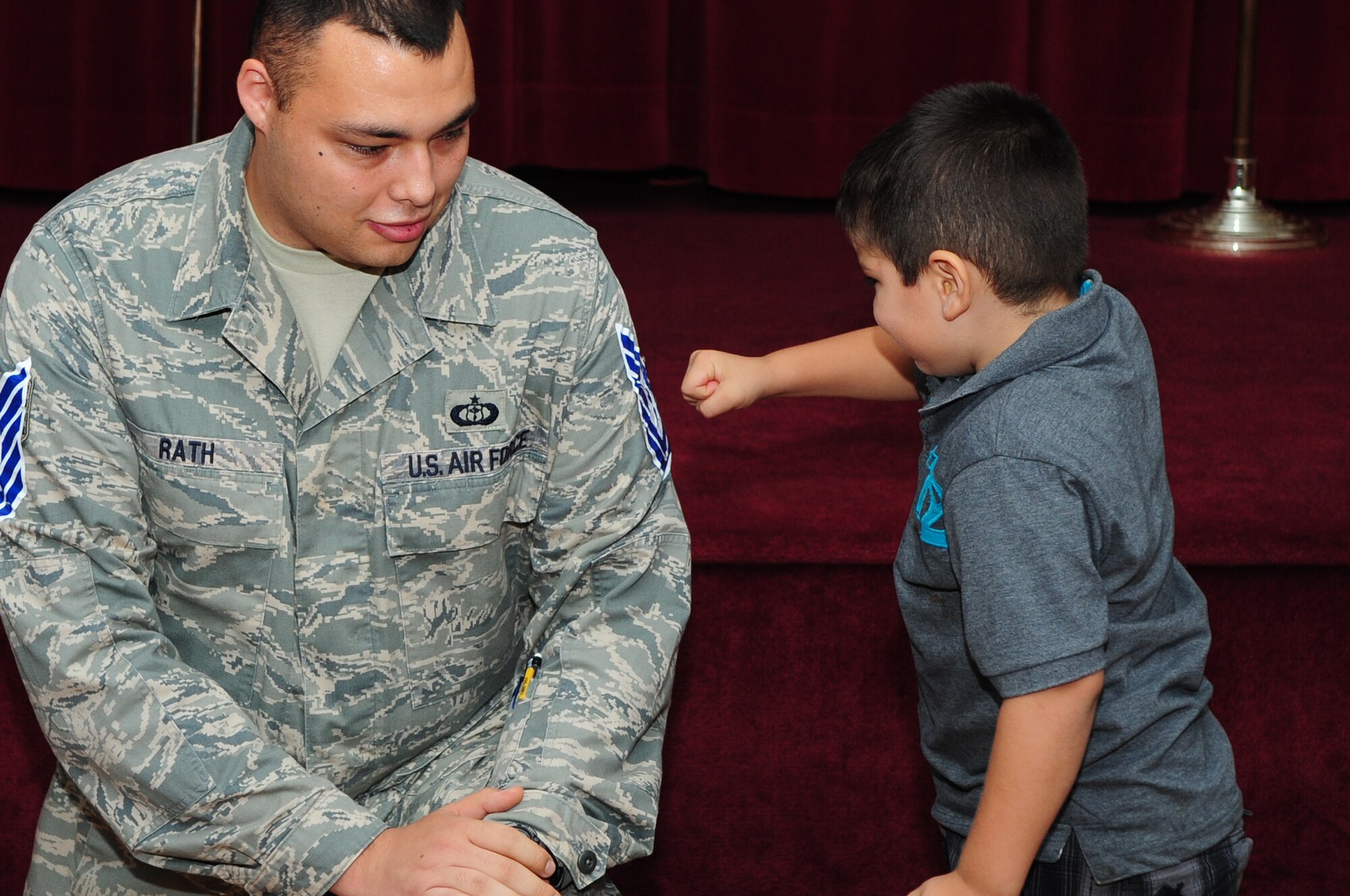 BARKSDALE AIR FORCE BASE, La. – Staff Sgt. Robert Rath, 26th Operational Weather Squadron, kneels down so his son can ‘tack on’ his new technical sergeant stripe during a promotion party held at the Stripes Club July 6. (U.S. Air Force photo by Senior Airman Joanna M. Kresge)