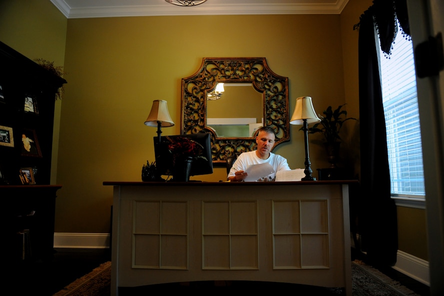 MOODY AIR FORCE BASE, Ga. -- Chief Master Sgt. Rodney Hoskinson quietly sits in a home office writing his speech while family members mingle in the living room before his retirement here July 8.  (U.S. Air Force photo by Staff Sgt. Gina Chiaverotti-Paige/RELEASED)