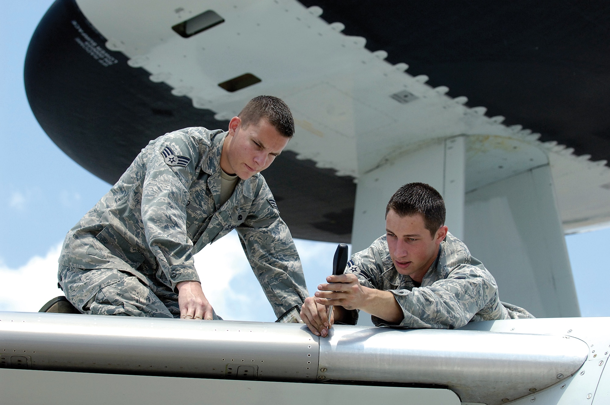 Senior Airman Matthew Child, left, and Airman 1st Class Joshua Martin are 552nd Aircraft Maintenance Squadron crew chiefs in the Red Aircraft Maintenance Unit.  Blistering summer days or the bite of winter doesn’t matter when it comes to making sure an E-3 Sentry is safe and ready to fly.  Working through a checklist they pour over a jet, tightening fasteners, checking for anything that needs attention.  Seeing “their” E-3 fly is a great feeling for them, knowing they had a hands-on to getting it airborne.  “Knowing I changed those tires, and to see it fly, that’s a pretty cool feeling,” said Airman Martin. (Air Force photo by Margo Wright)