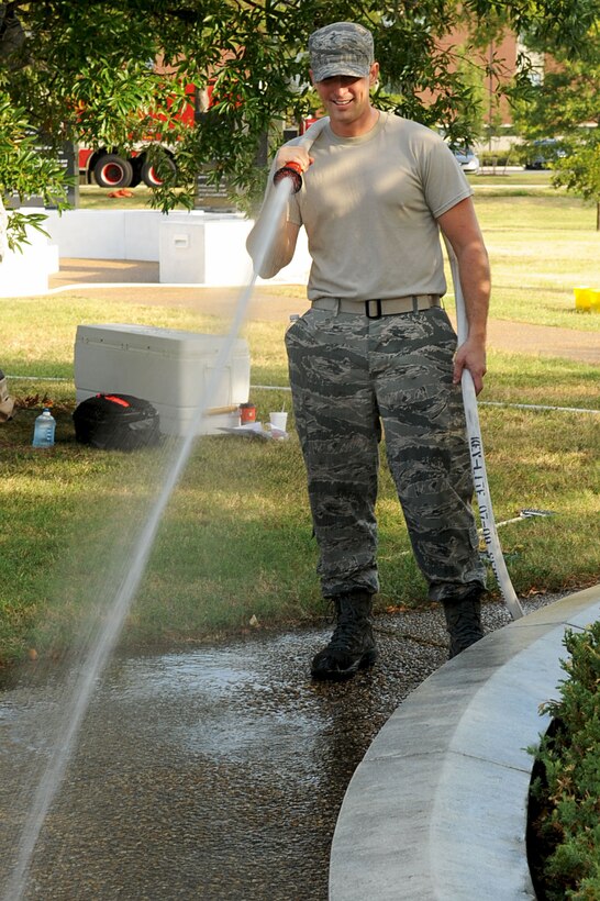 LANGLEY AIR FORCE BASE, Va. -- Staff Sgt. Joseph Dunn, 633d Civil Engineer Squadron fire department crew chief, sprays away dirt and debris during the July 9 POW/MIA Memorial and mediation garden clean-up. The Air Force Sergeants Association and the 633d Logistics Readiness Squadron Unit Advisory Council coordinated the event to boost morale with their Airmen. (U.S. Air Force photo/Staff Sgt. Ashley Hawkins)