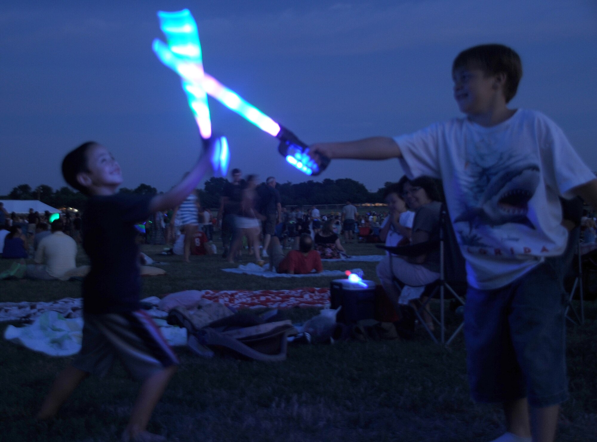 Antonio Jimenez, 6, and Anthony Naronski, 10, fence with their lighted swords at Doughboy Field during the Fourth of July celebration. The highlight of the celebration was the night-capped fireworks display. (U.S. Air Force photo/Senior Airman David Carbajal)