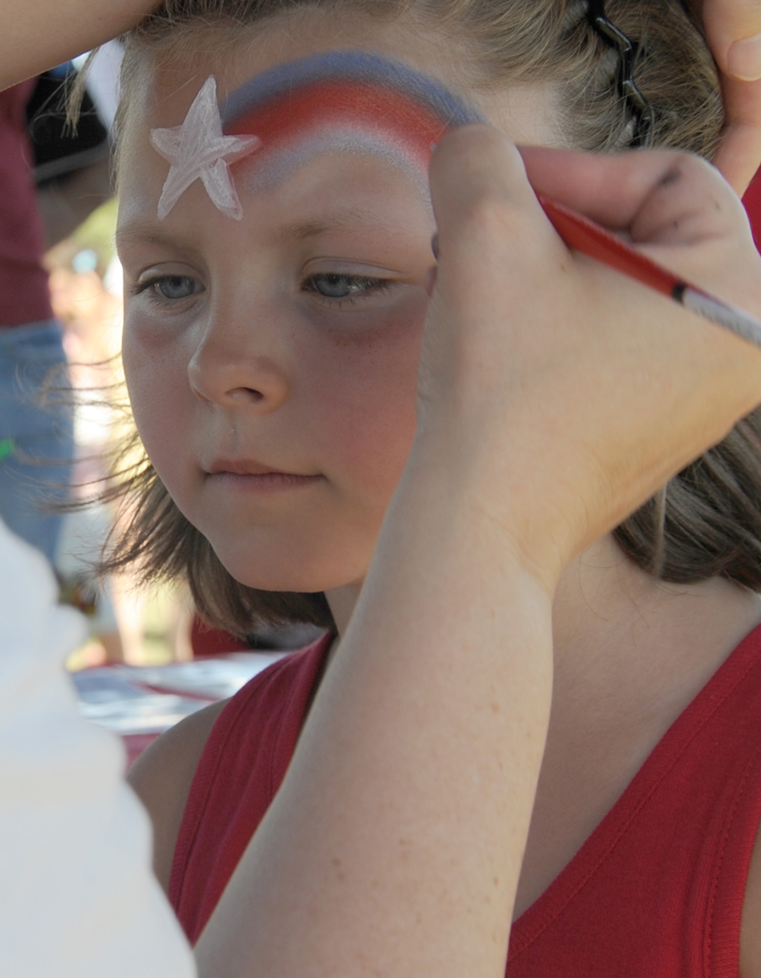 Mackenzie Springman, 6, gets her face painted at Doughboy Field during the Fourth of July celebration. Children were given the opportunity to get their face painted, receive custom balloon animals from balloonist and play in bouncy castles during the celebration. (U.S. Air Force photo/Senior Airman David Carbajal)