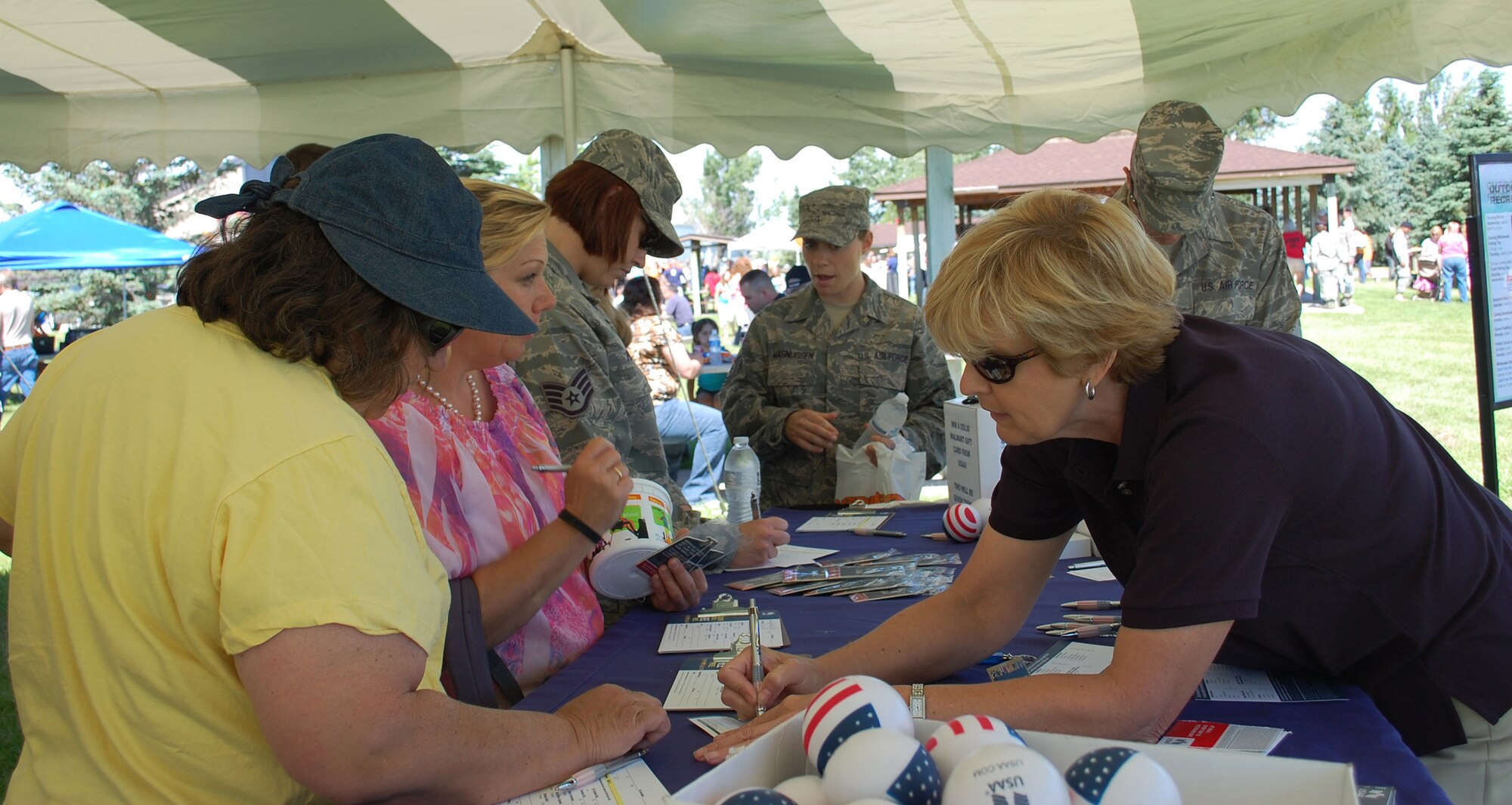 USAA representative Audrey Thompson explains some information to Joann Kiernan while other interested people look over information on the orgranization. USAA was one of the many booths on hand to give out information to those attending the free annual event July 1. (U.S. Air Force photo/Valerie Mullett)