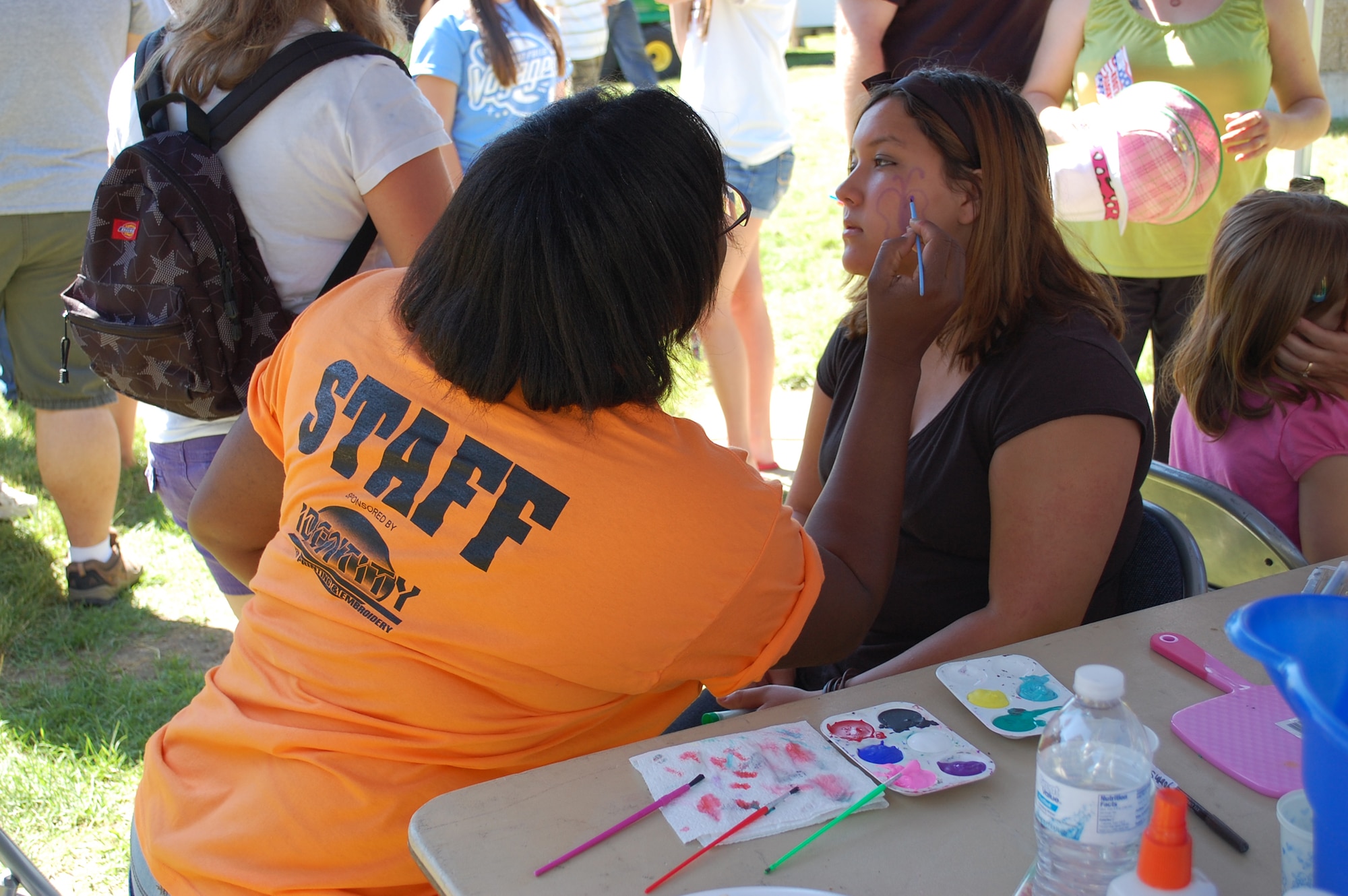 Child Development Center employee Diane Williams paints a butterfly on the cheek of Monica Payan, 14. The face painting and tattoo booth was a popular attraction at the base picnic July 1. (U.S. Air Force photo/Valerie Mullett)