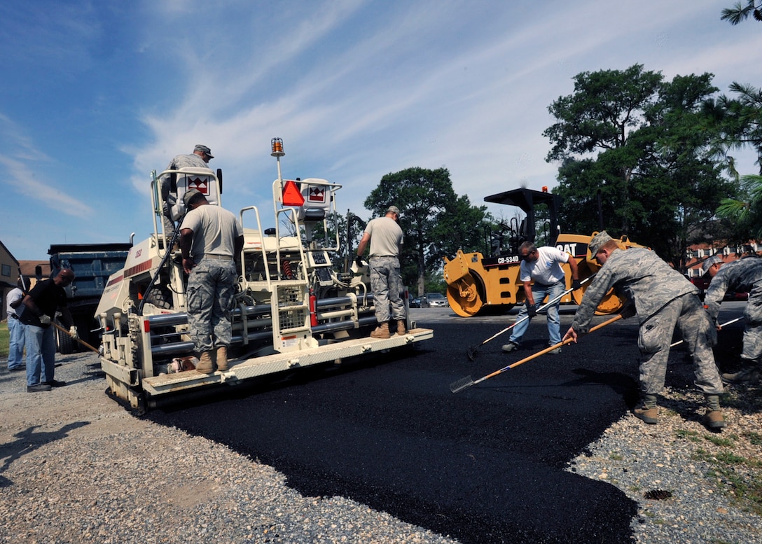JOINT BASE ANDREWS, Md. -- A cadre of 316th Civil Engineer Squadron military and civilian members work in unison as they use an asphalt paver to smooth asphalt on the parking lot of Structural West Carpentry Shop, building 1527, July 1. The crew of workers laid approximately 150 tons of asphalt. (U.S. Air Force photo by Bobby Jones)