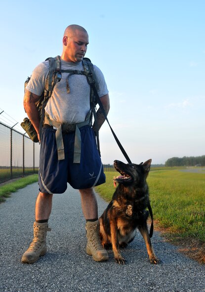 MOODY AIR FORCE BASE, Ga. -- Staff Sgt. David Smith, 23rd Security Forces Squadron military working dog handler, looks down at Liza, 23rd SFS military working dog, as she looks up at him during the playing of reveille during a physical training session here June 25. Two of the most important things to have between the handler and the MWD are trust and teamwork. (U.S. Air Force photo by Airman 1st Class Joshua Green/RELEASED)