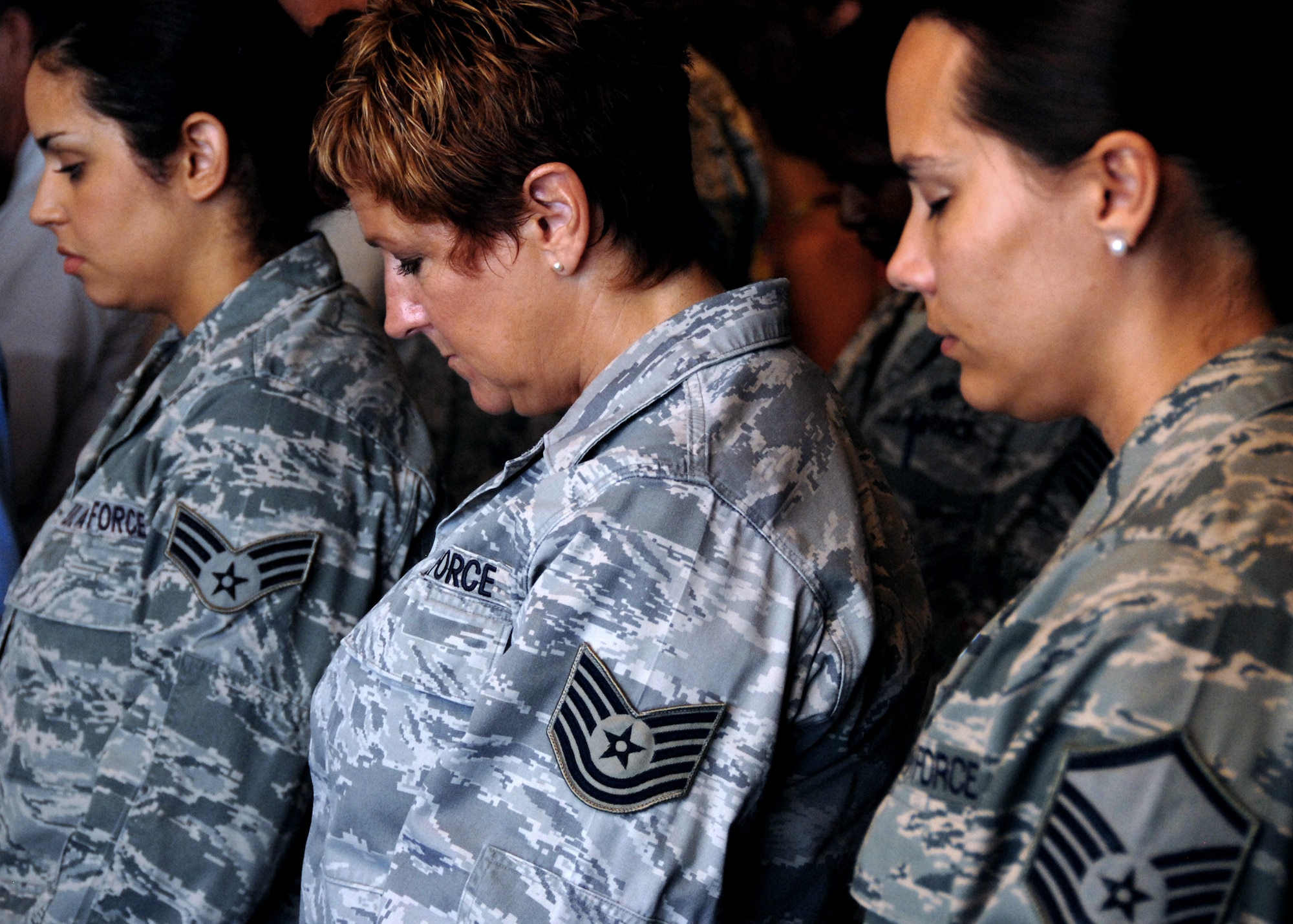 Three women representing the tiers of Air Force enlisted ranks pause during the invocation during the 96th Air Base Wing change of command July 8 at the officers club.  Col. Sal Nodjomian took command of the wing from departing commander, Col. Bruce McClintock.  (U.S. Air Force photo/Samuel King Jr.)