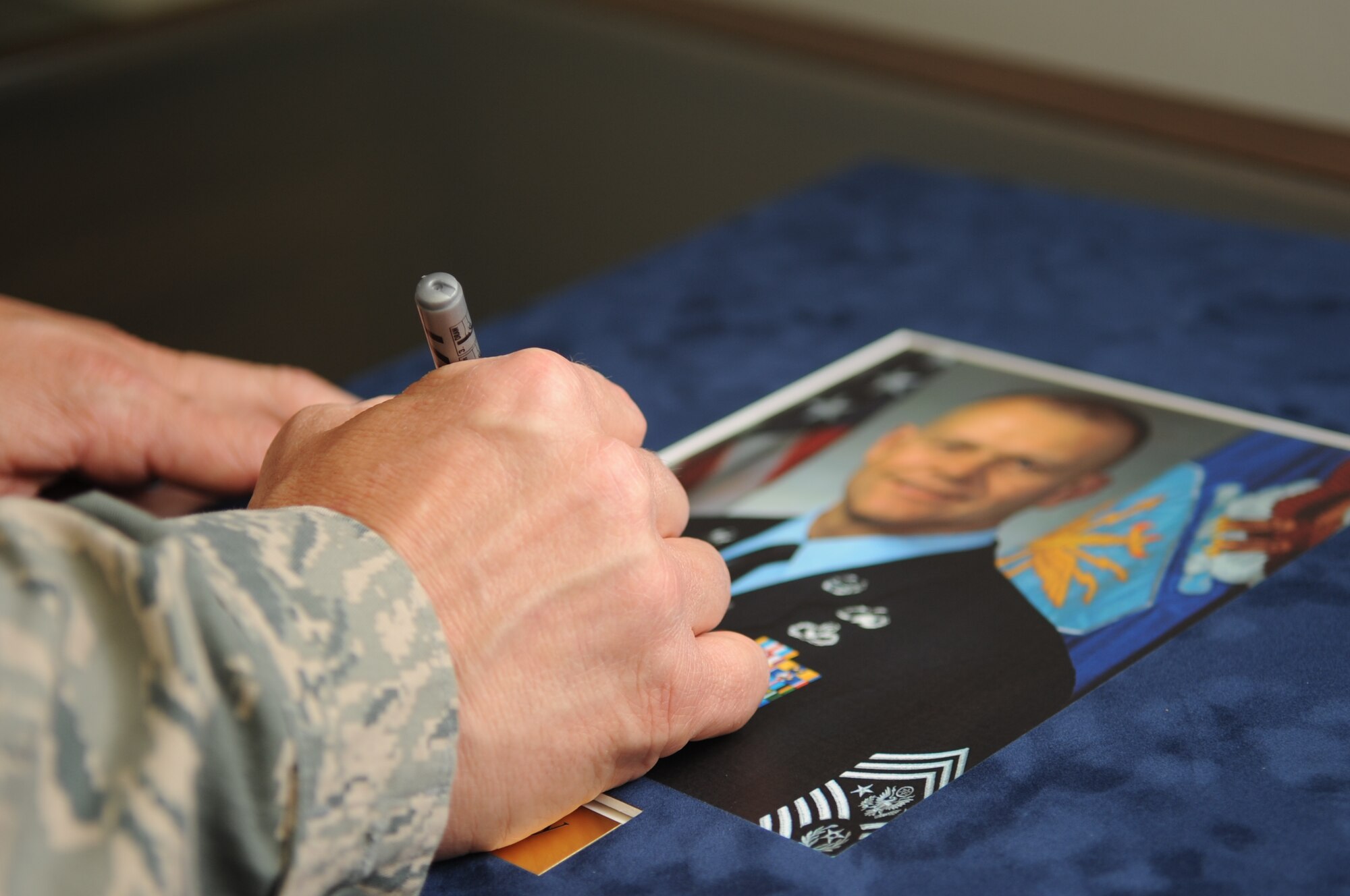 SPANGDAHLEM AIR BASE, Germany – Chief Master Sgt. of the Air Force James Roy signs an official photograph of himself for the Pitsenbarger Airman Leadership School while touring the base July 8. Chief Roy visited the 52nd Fighter Wing to see firsthand how U.S. Air Forces in Europe Airmen contribute to the fight while partnering with joint and coalition forces worldwide. He and his wife, Paula Roy, visited various locations such as the 52nd Maintenance Group, the 52nd Civil Engineer Squadron, the 52nd Communications Squadron, the 52nd Security Forces Squadron and the 606th Air Control Squadron. (U.S. Air Force photo/Airman 1st Class Nick Wilson)