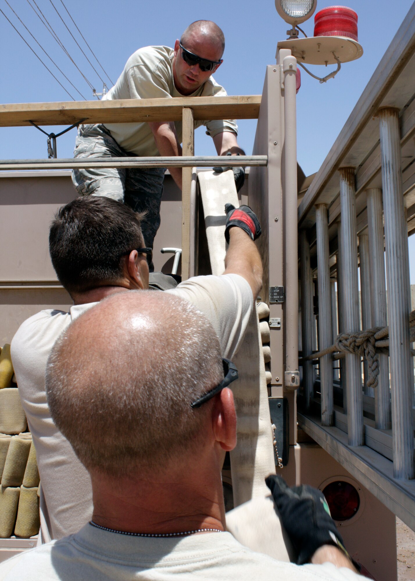 Tech Sgt. James Maynard, Senior Airman Jordan Davenport and Tech. Sgt. Brian Williams, 332nd Expeditionary Civil Engineer Squadron Fire Emergency Services Flight firefighters, carefully stack fire hoses into one of the trucks after a training exercise in a housing area July 3, 2010, at Joint Base Balad, Iraq. Fire hoses are stacked in certain ways on trucks to ensure they do not fall out during high-speed travel, and to make it easier to pull them down once the firefighters arrive on site. Sergeant Maynard is deployed from Cannon Air Force Base, N.M., Airman Davenport is deployed from Barksdale AFB, La., and Sergeant Williams is deployed from Eielson AFB, Alaska. (U.S. Air Force photo/Staff Sgt. Stacy Fowler)
