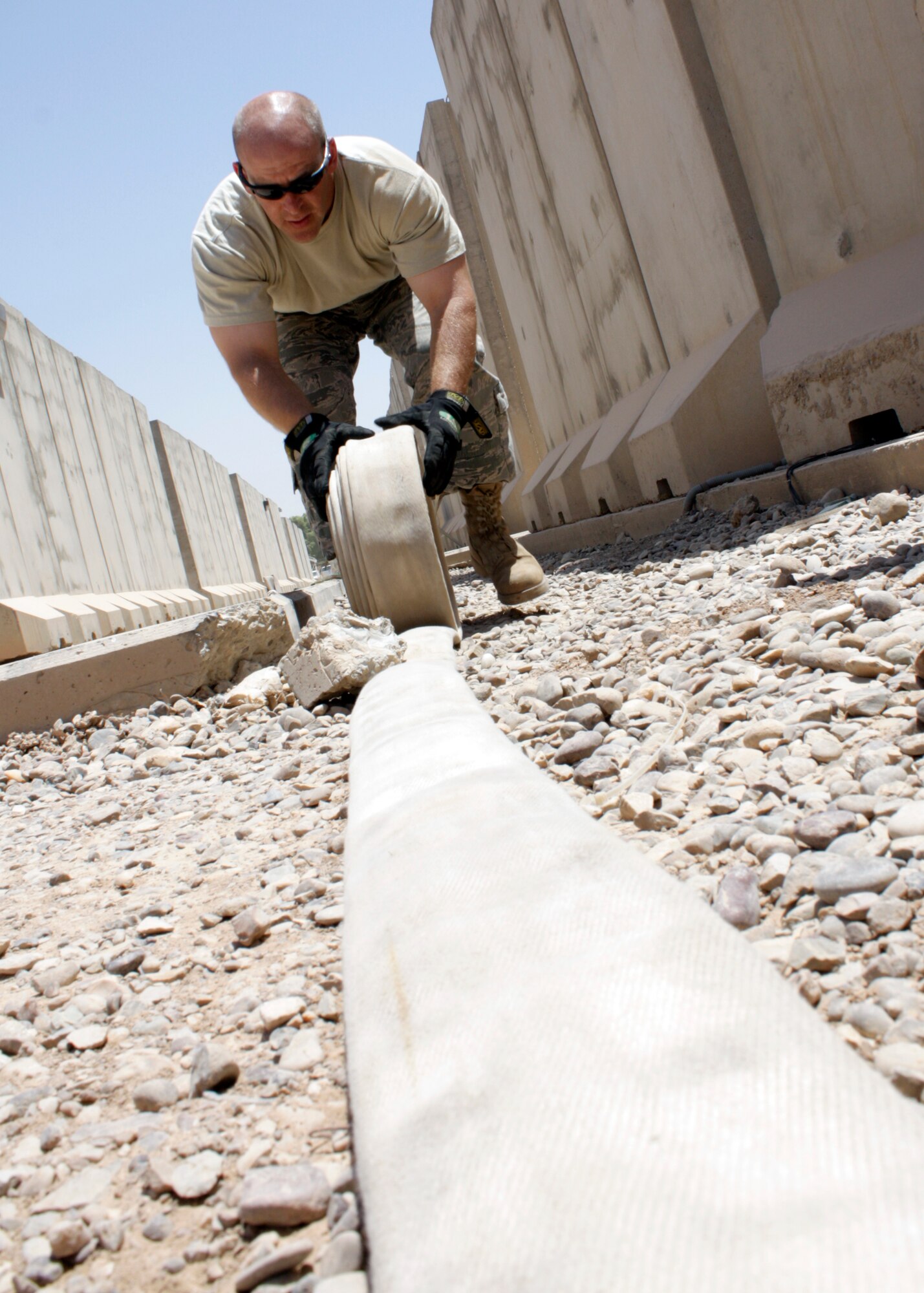 Tech. Sgt. Brian Williams, 332nd Expeditionary Civil Engineer Squadron Fire Emergency Services Flight firefighter, rolls up a fire hose after a training exercise in a housing area July 3, 2010, at Joint Base Balad, Iraq. Ensuring the fire hoses are completely emptied of water help keeps the overall wear and tear to manageable levels, especially in an austere environment like Balad. Sergeant Williams is deployed from Eielson Air Force Base, Alaska. (U.S. Air Force photo/Staff Sgt. Stacy Fowler)