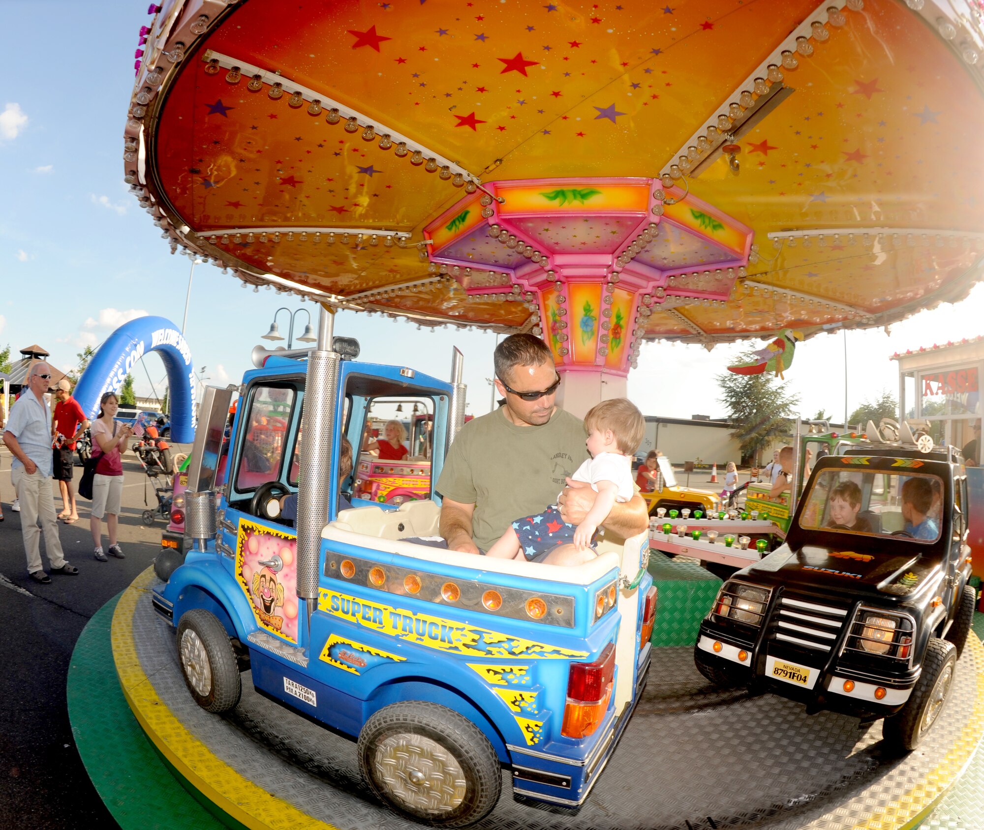 SPANGDAHLEM AIR BASE, Germany – Tech. Sgt. Alan Turner, 52nd Civil Engineer Squadron pavements and equipment craftsman, holds his 11-month-old son at a merry-go-round during Super Saber Appreciation Day July 4. The day also included live bands, various activity booths, free food, a pet show and fireworks. (U.S. Air Force photo/Airman 1st Class Nick Wilson)