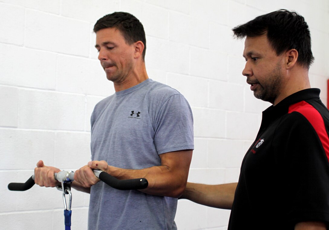 Ron S. Rivera, fitness center supervisor, right, helps Petty Officer First Class David Mercil, travel coordinator, Navy Public Affairs Support Element West, Coronado, Calif., execute a test that calculates maximum bicep strength during the Men’s Health Fair here, June 11. This test is part of Micro-Fit, which gives a basic assessment of where an individual stands on a physical fitness level.