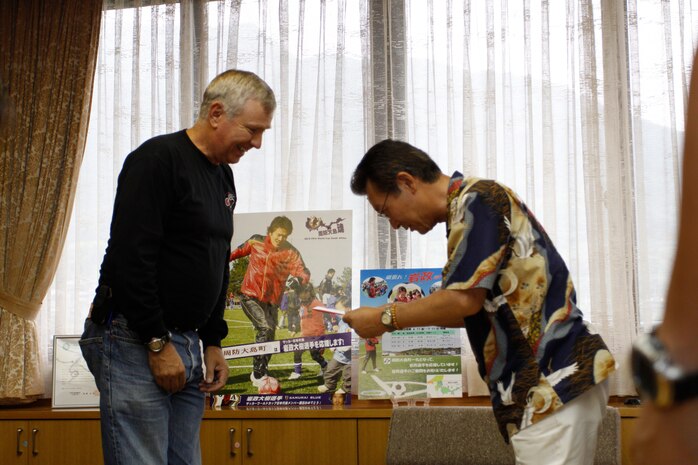 Takumi Shiiki, Oshima Island mayor receives a donation of ¥200,000 from Michael Gingles, Iwakuni Motorcycle Club president at the Oshima Island town hall July 9. The money donated was raised during this year’s annual two-day motorcycle rally organized by the Iwakuni Motorcycle Club this past April 10 and 11.