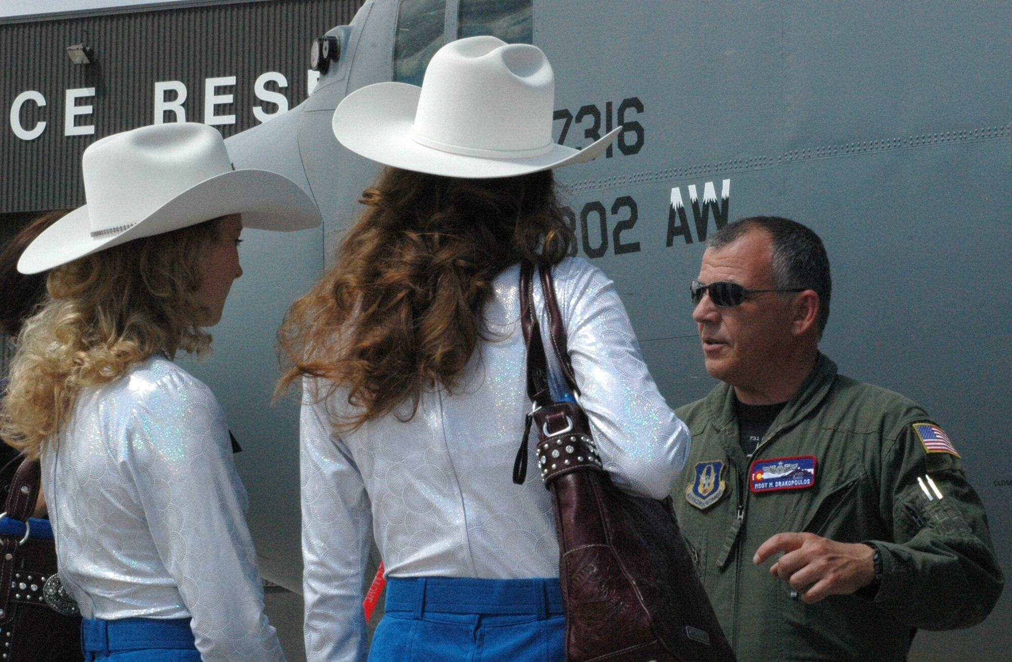 Master Sgt. Miltiadis "Drak" Drakopoulos explains to Girls of the West ladies Jessica Greene (left) and Dayna Jenkins what it's like to be a loadmaster on a C-130 Hercules aircraft July 1 at Peterson Air Force Base, Colo. Both Miss Greene, the Girl of the West, and her aide, Miss Jenkins, received an up-close look at the 302nd Airlift Wing's primary mission of tactical airlift and airdrop and experienced a re-enlistment ceremony for an enlisted member. Sergeant Drakopoulos is a C-130 loadmaster assigned to the 731st Airlift Squadron. The 302nd AW is an AF Reserve-assigned unit also charged with mission of aerial firefighting using the Modular Airborne Firefighting System. For more information on the Girls of the West, visit www.coloradospringsrodeo.com. (U.S. Air Force photo/Staff Sgt. Stephen J. Collier)