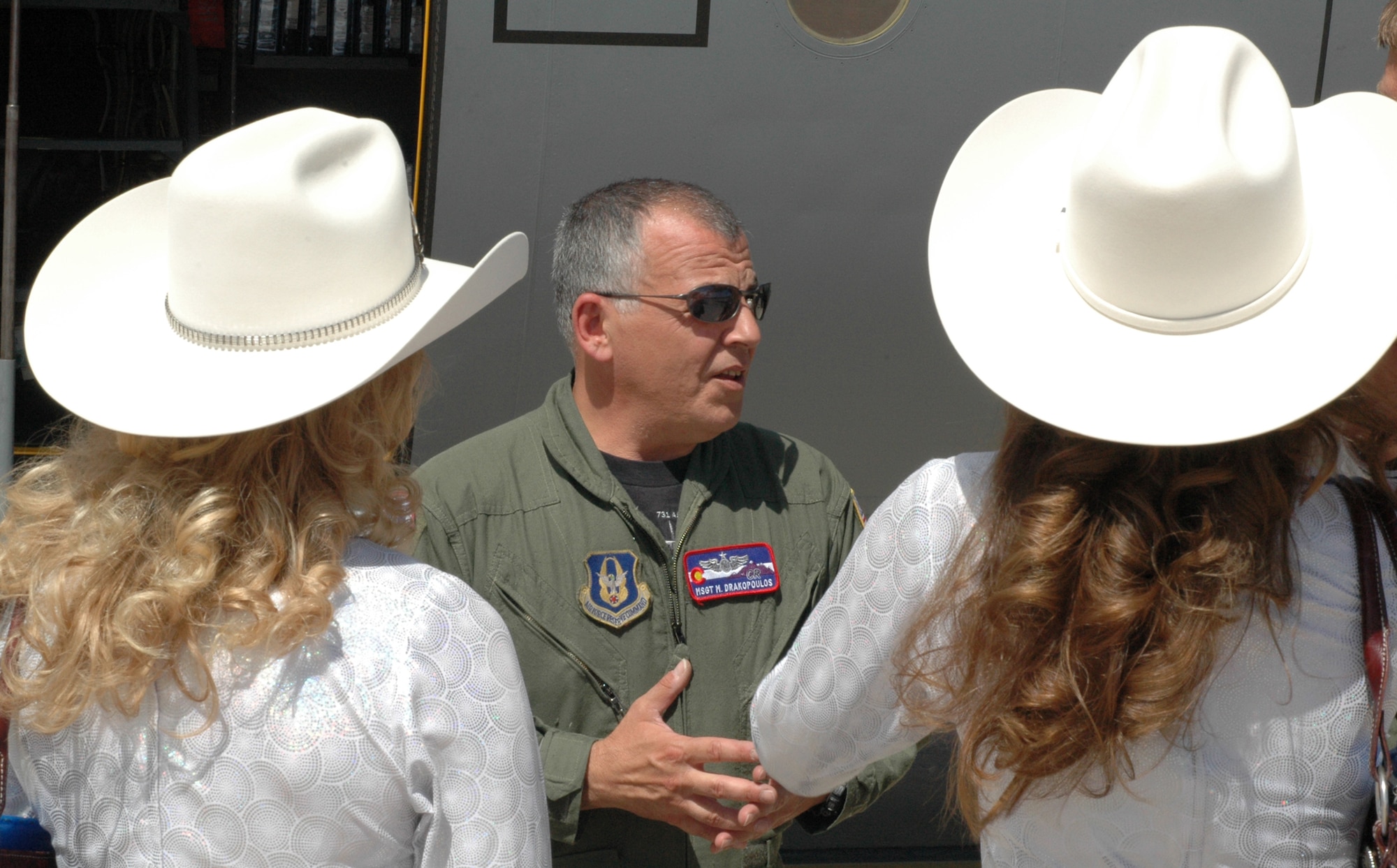 Master Sgt. Miltiadis "Drak" Drakopoulos explains to Girls of the West ladies Jessica Greene (left) and Dayna Jenkins the capabilities of the 302nd Airlift Wing's C-130 Hercules aircraft July 1 at Peterson Air Force Base, Colo. Both Miss Greene, the Girl of the West, and her aide, Miss Jenkins, received an up-close look at the 302nd Airlift Wing's primary mission of tactical airlift and airdrop and experienced a re-enlistment ceremony for an enlisted member. Sergeant Drakopoulos is a C-130 loadmaster assigned to the 731st Airlift Squadron. The 302nd AW is an AF Reserve-assigned unit also charged with mission of aerial firefighting using the Modular Airborne Firefighting System. For more information on the Girls of the West, visit www.coloradospringsrodeo.com. (U.S. Air Force photo/Staff Sgt. Stephen J. Collier)
