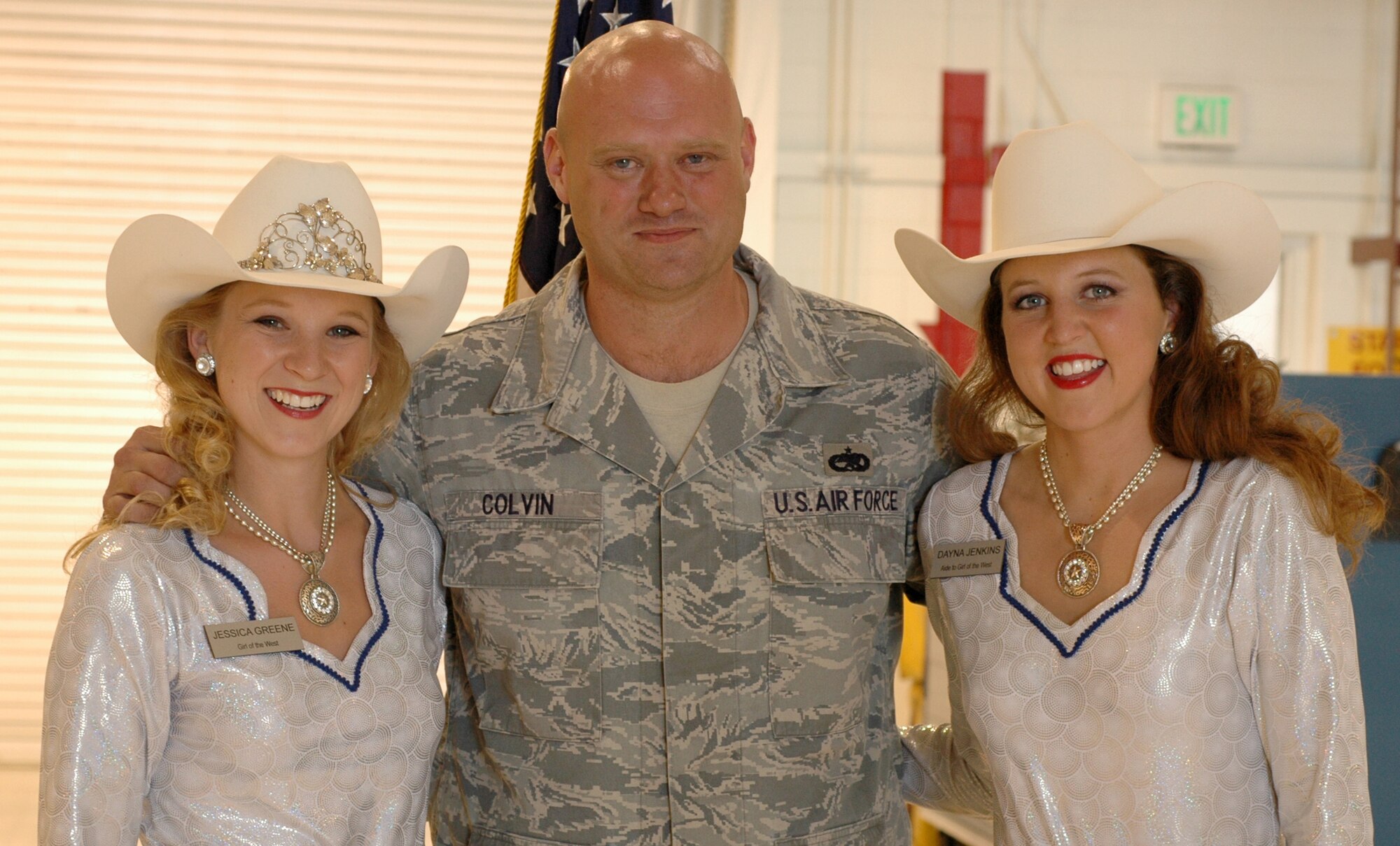 Girls of the West ladies Jessica Greene (left) and Dayna Jenkins stop for a photo with Tech. Sgt. Kennon Colvin after he re-enlisted with the Air Force July 1 at Peterson Air Force Base, Colo. Both Miss Greene, the Girl of the West, and her aide, Miss Jenkins, received an up-close look at the 302nd Airlift Wing's primary mission of tactical airlift and airdrop and experienced the re-enlistment ceremony for the 52nd Airlift Squadron member. Sergeant Colvin is a C-130 crew chief assigned to the 52nd AS, an Active Duty C-130 unit associated with the 302nd AW. The 302nd AW is an AF Reserve-assigned unit also charged with mission of aerial firefighting using the Modular Airborne Firefighting System. For more information on the Girls of the West, visit www.coloradospringsrodeo.com. (U.S. Air Force photo/Staff Sgt. Stephen J. Collier)