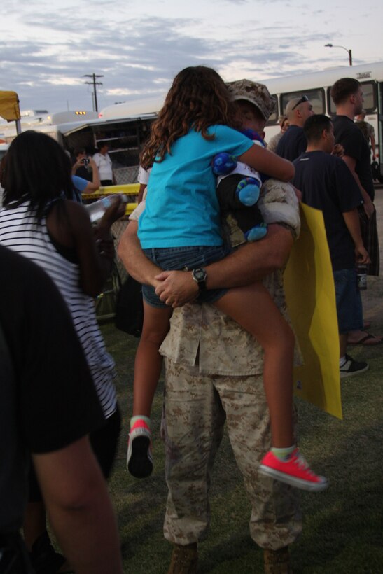 MARINE CORPS AIR GROUND COMBAT CENTER TWENTYNINE PALMS, Calif.--Gunner Brett Turek holds his daughter Katie Turek upon return with the 2d Battalion 7th Marine Regiment from the 31st Marine Expeditionary Unit July 12 at the Del Valle softball field.