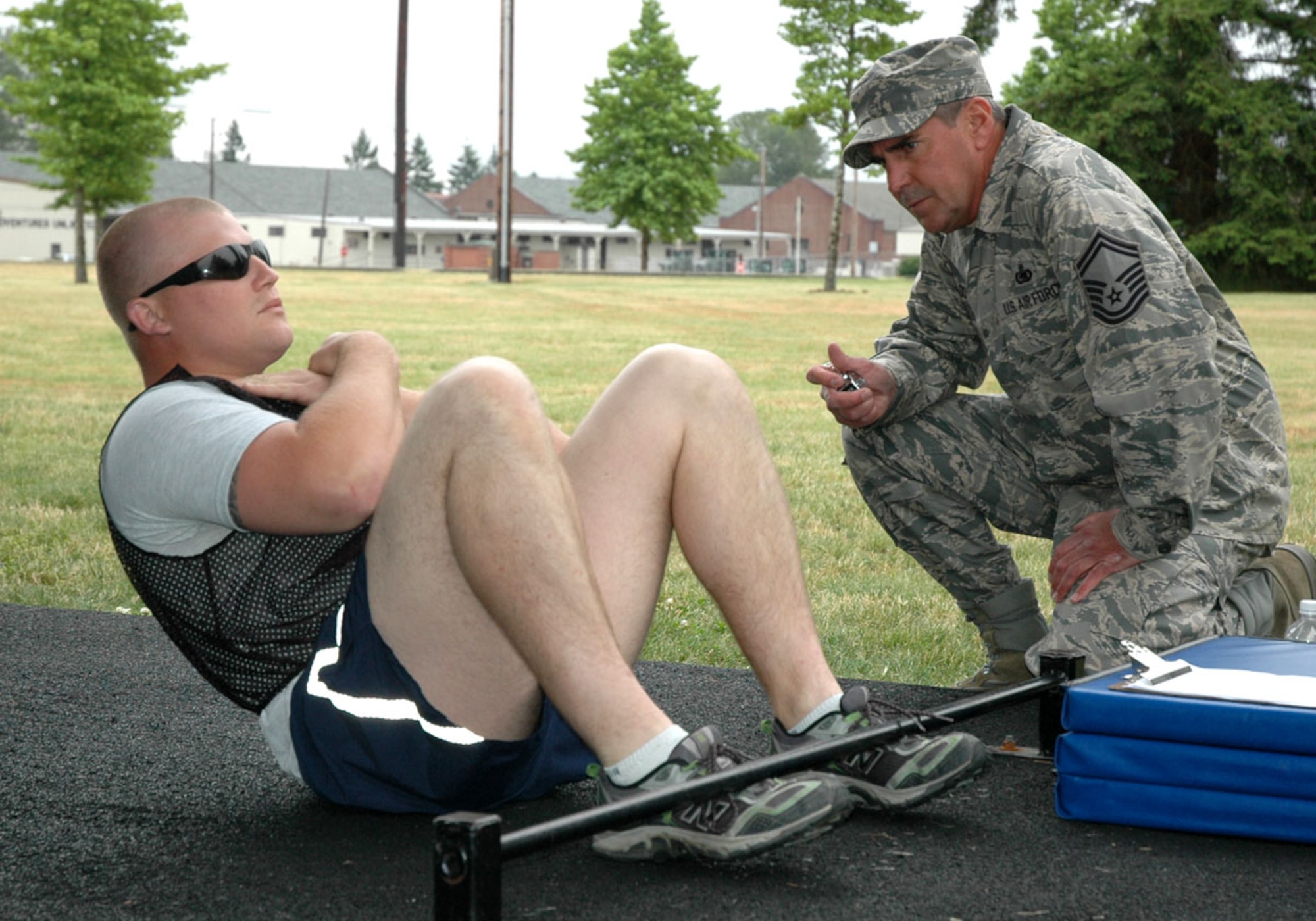 JOINT BASE LEWIS-MCCHORD, Wash. -- Staff Sgt. Karl Renfro, 446th Logistics Readiness Flight, demonstrates proper form situps under the watchful eye of his fitness monitor, Senior Master Sgt. Jeff Doll, 446th LRF, during a fitness assessment here July 10, 2010.  The new Air Force fitness program took effect July 1. The program will hold Airmen to more rigourous physical fitness standards in an effort to improve overall health and readiness. (U.S. Air Force photo/Staff Sgt. Grant Saylor)