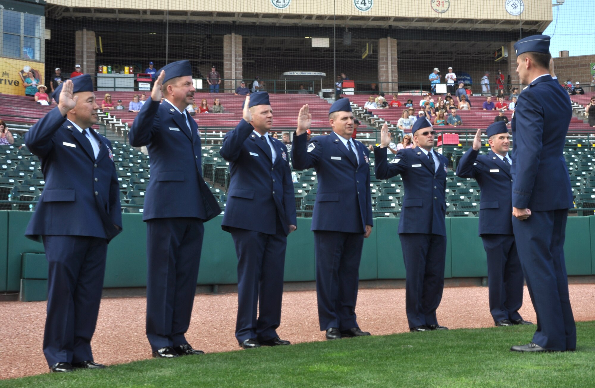 Air Force Reserve and Active Duty Maintenance Airmen recite the oath of enlistment administered by Col. James Van Housen (right) July 10 at Security Service Field in Colorado Springs, Colo. Five of the Airmen, assigned to the 302nd Maintenance Group, and one Airman from the 52nd Airlift Squadron, are based at nearby Peterson Air Force Base. Members of the 302nd MXG, assigned to the AF Reserve's 302nd Airlift Wing, worked with the city's Sky Sox minor league baseball team to re-enlist the six Airmen in front of an estimated 3,000-person crowd. Later that evening, Airman 1st Class Tyler Higgins from the 52nd AS threw out the first pitch against the visiting Reno Aces during the night's doubleheader. Colonel Van Housen is the 302nd MXG commander. (U.S. Air Force photo/Staff Sgt. Stephen J. Collier)