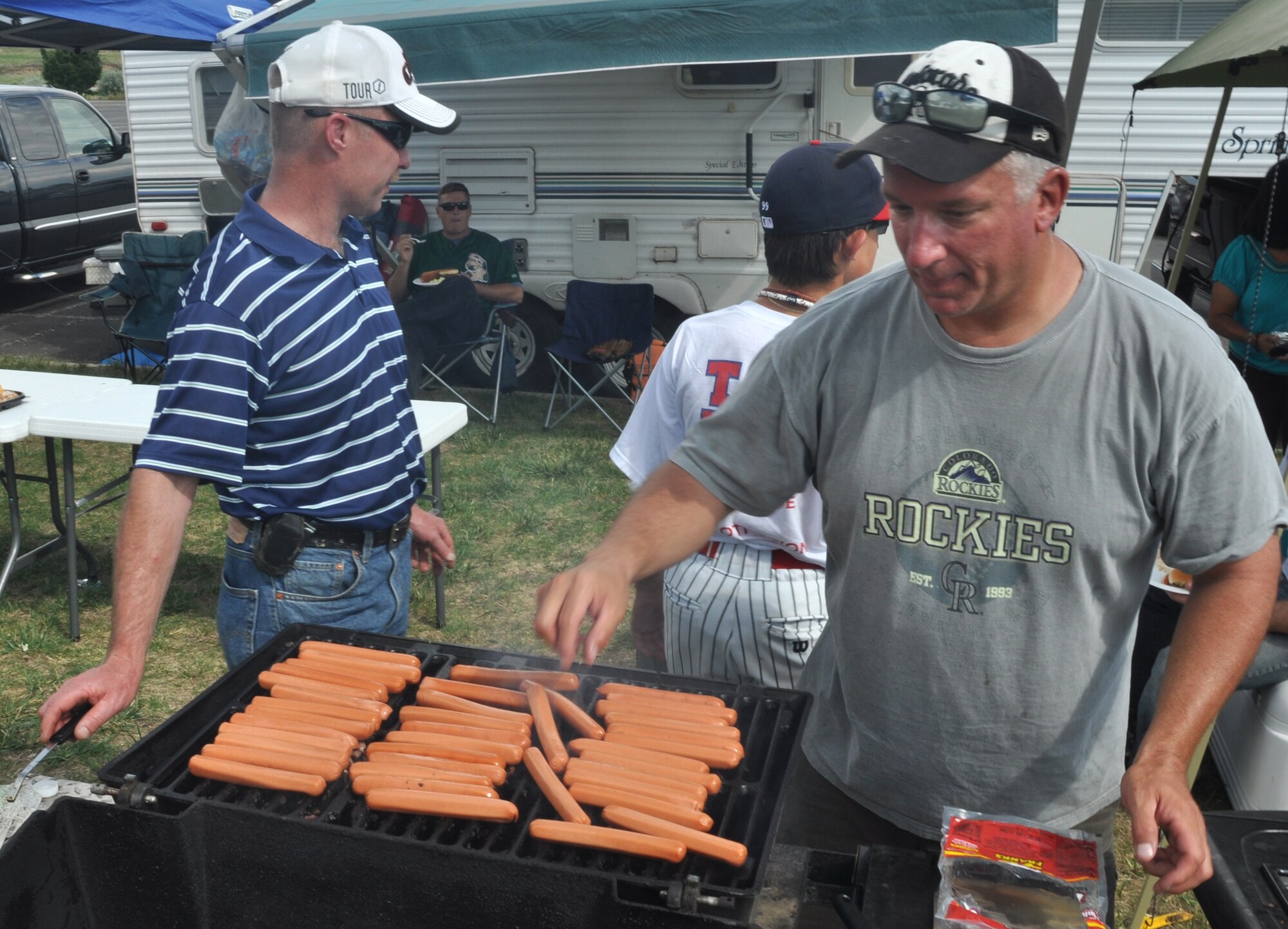 Senior Master Sgt. Michael Sinchak (right) adds another hot dog to the grill July 10 with the help of Master Sgt. Todd Baird (left) during a 302nd Maintenance Group outing at Security Service Field in Colorado Springs, Colo. The 302nd MXG, assigned to the Air Force Reserve's 302nd Airlift Wing at nearby Peterson Air Force Base, worked with the city's Sky Sox minor league baseball team to re-enlist five AF Reservists and one Active Duty Airmen in front of an estimated 3,000-person crowd.  Sergeant Sinchak is the 302nd Maintenance Squadron communication and navigation section chief, while Sergeant Baird is the 302nd MXS electronic countermeasures shop chief. (U.S. Air Force photo/Staff Sgt. Stephen J. Collier)