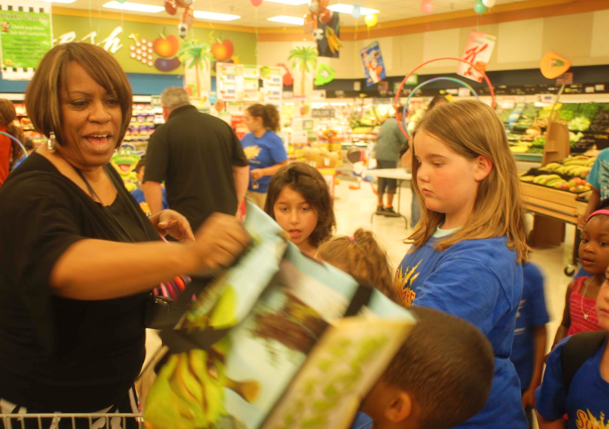 Cheryl Varner, March Commissary produce manager, hands bags of healthy treats to kids as they prepare to return to their day care center. Commissary vendors donated the bags and items inside.  (U.S. Air Force photo by Megan Just)