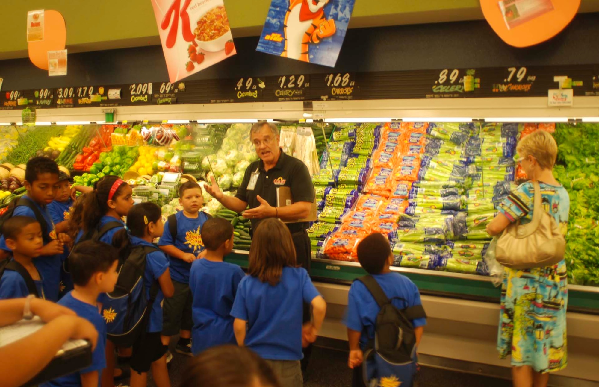 A commissary shopper selects a bag of celery as Steve Hass, a produce merchandiser, teaches Moreno Valley children about the benefits of eating fresh fruits and vegetables. The March Commissary employees planned the produce department event as a fun way for kids to learn about healthy eating and exercise. (U.S. Air Force photo by Megan Just)