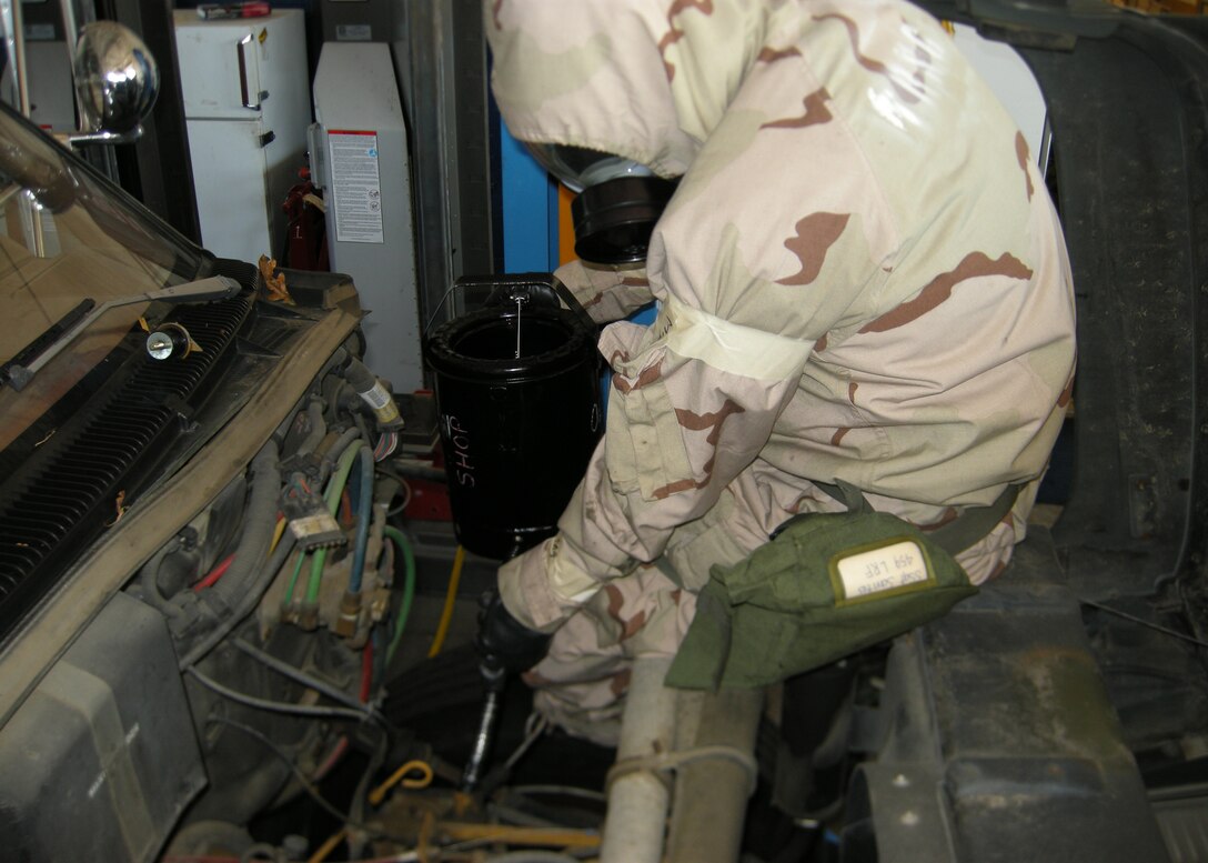 Staff Sgt. Nanerico Santos, 459th Logisitics Readiness Flight, performs maintance on a government vehicle while wearing his chemical warfare suit, here July 11. Airmen from the 459th Air Refueling Wing participated in chemical and biological warfare training during the July Unit Training Assembly in preparation for an upcoming Operational Readiness Inspection. (U.S. Air Force photo/Senior Airman Darryl Brodie)                               