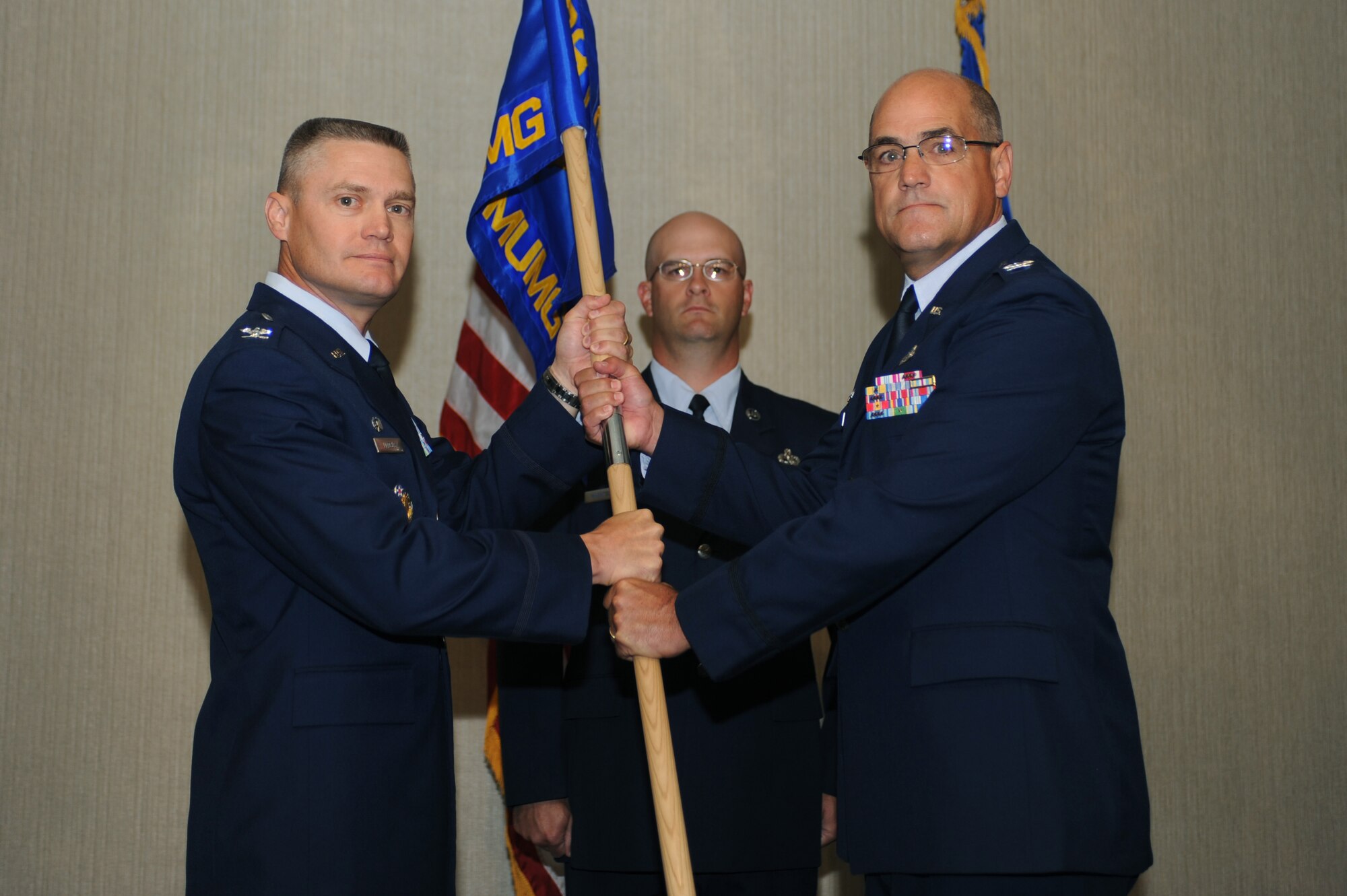 MINOT AIR FORCE BASE, N.D. -- Presiding officer Col. Walter Lindsley, 498th Nuclear Systems Wing commander at Kirtland AFB, N.M., passes the ceremonial flag to Col. Phillip Boroff, 798th Munitions Maintenance Group commander, traditionally signifying the assumption of command over the 798th MUMG here July 12. The 798th MUMG standup is an important step toward establishing support for Air Force Global Strike Command, which is the lead major command for Air Force nuclear operations. (U.S. Air Force photo by Airman 1st Class Aaron-Forrest Wainwright)