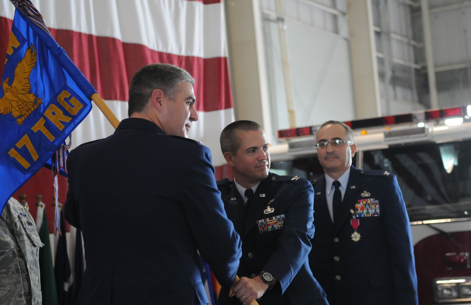 Col. Thomas Geary, 17th Training Wing commander, passes the 17th Training Group guideon to the group's new commander, Col. J.D. Willis, July 9 as Col. Anthony Lombardo, former 17th TRG commander, looks on. (U.S. Air Force photo/Airman 1st Class Clayton Lenhardt)