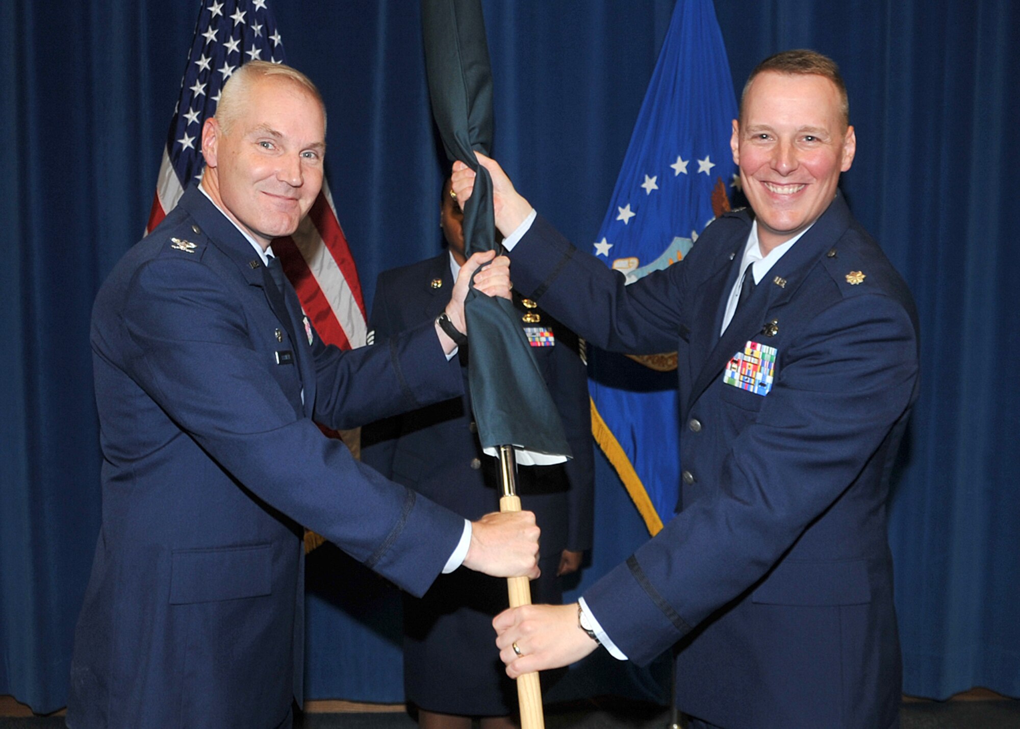 Col. Matthew Bartlett, 377th Mission Support Group commander, left, and Lt. Col. John Leif, 377th Contracting Squadron commander, hold the covered 377th CONS guidon, signifying inactivation during a ceremony June 30. The Contracting Squadron is now a division of the Air Force Nuclear Weapons Center Contracting Directorate.  U.S. Air Force Photo by Todd Berenger.