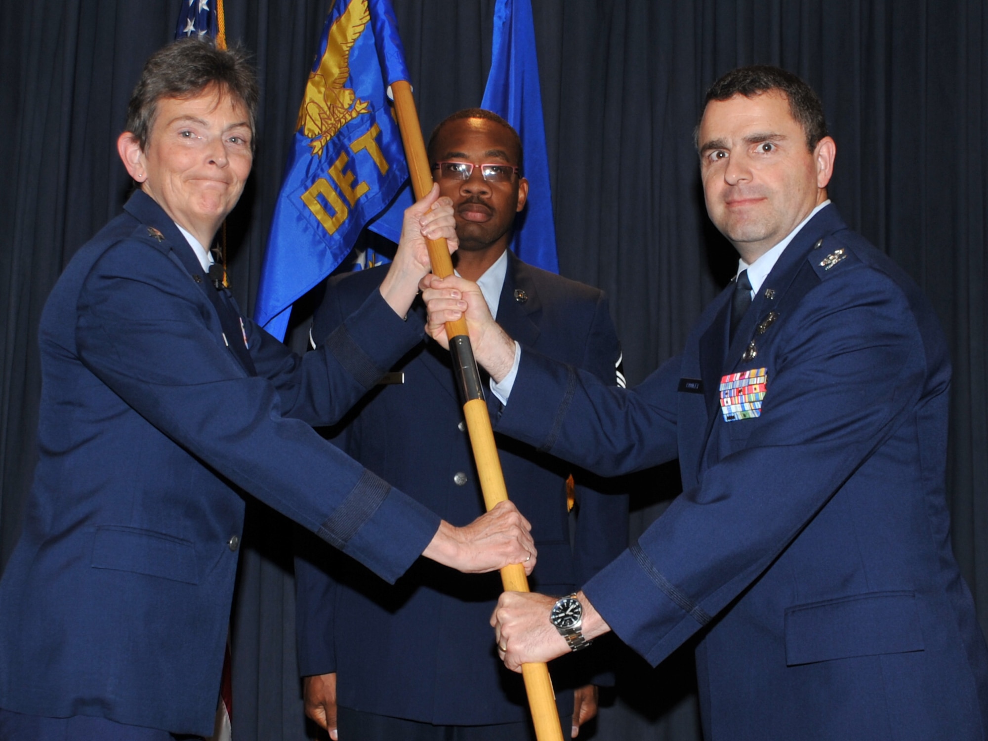 Maj. Gen. Ellen M. Pawlikowski, Air Force Research Laboratory commander, left, passes the AFRL Space Vehicles guidon to Col. William T. Cooley during a change-of-command ceremony July 1.  U.S. Air Force Photo by Todd Berenger
