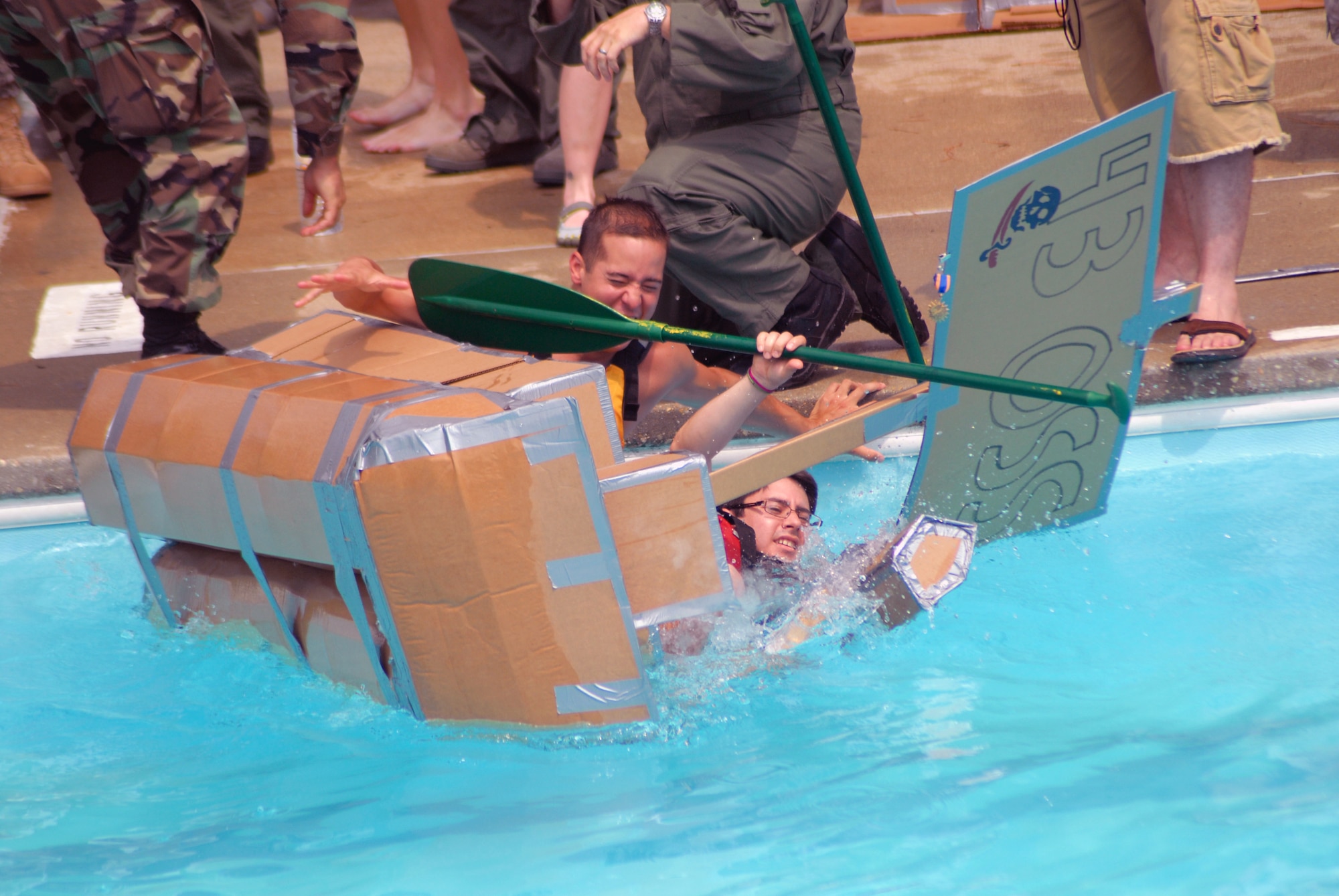 Staff Sgts. Nickolas Mann (front) and Kelly Alarcon, 43rd Operations Support Squadron, fall into the Pope Pool during the Pope Regatta July 8. The team’s boat did not make it halfway across the pool and won the Titanic Award for the best sinking ship during the Regatta.  (U.S. Air Force Photo/1st Lt. Cammie Quinn)