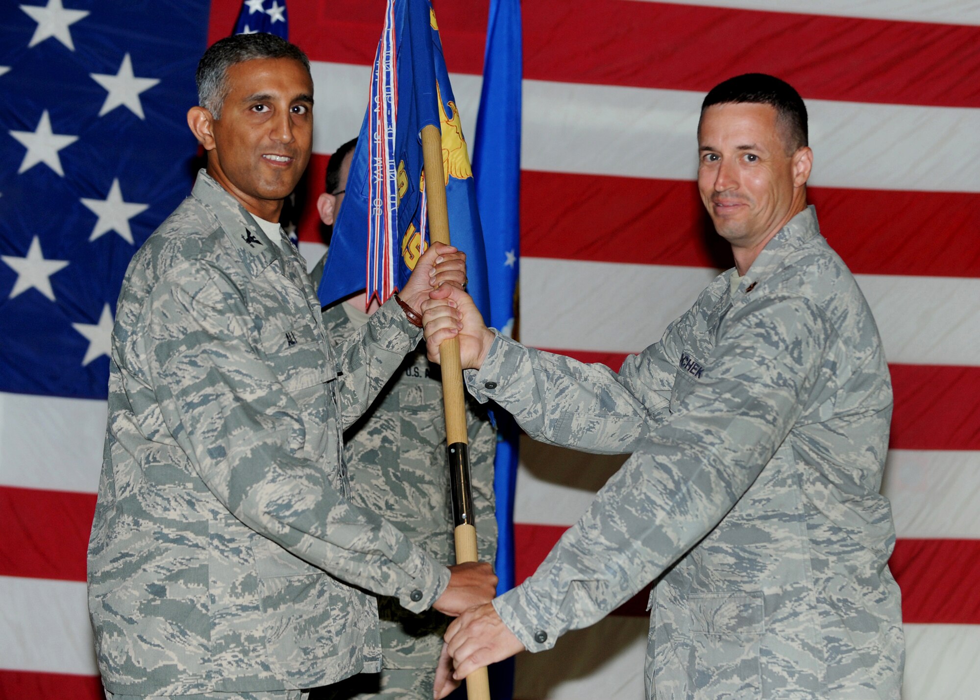 SOUTHWEST ASIA - Col. Rizwan Ali (left), 386th Expeditionary Mission Support Group commander, passes the 386th Expeditionary Contracting Squadron guidon to Maj. John Wodochek, the new 386th ECONS commander, during a change-of-command ceremony at an undisclosed air base here July 12, 2010. Major Wodochek assumed command after Maj. Robert McCabe relinquished command. (U.S. Air Force photo by Senior Airman Laura Turner)