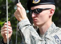 Senior Airman Zachary Mabes, 919th Security Forces Squadron, begins to bring down the flag while practicing a flag-raising ceremony July 11 at Duke Field. (U.S. Air Force photo/Tech. Sgt. Samuel King Jr.)