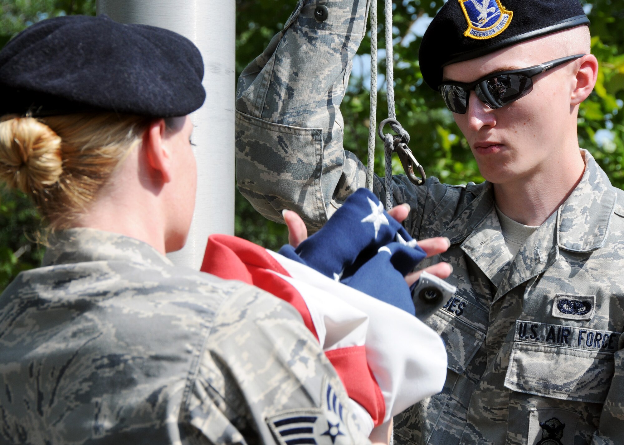 Senior Airman Zachary Mabes, 919th Security Forces Squadron, holds the rope while another Airman unhooks the flag while practicing a flag-raising ceremony July 11 at Duke Field. (U.S. Air Force photo/Tech. Sgt. Samuel King Jr.)
