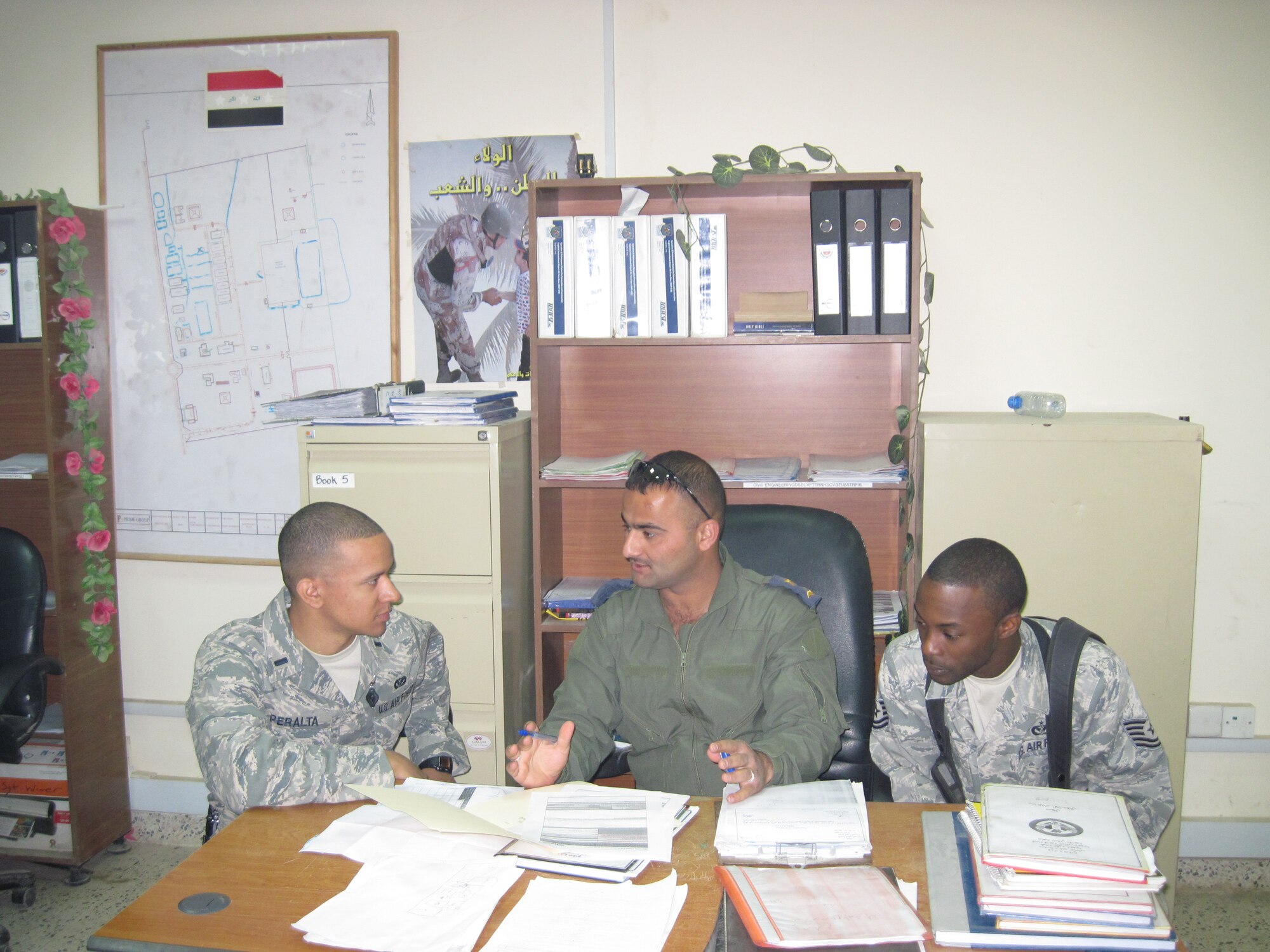 1st Lt. Harold Peralta (left) and Tech. Sgt. Michael Elmore, (right) both with the 321st Expeditionary Mission Support and Advising Squadron, discuss the progress of a construction project with their Iraqi Counterpart at a base in Iraq. Lieutenant Peralta is deployed from Pope’s 43rd Civil Engineer Squadron.
