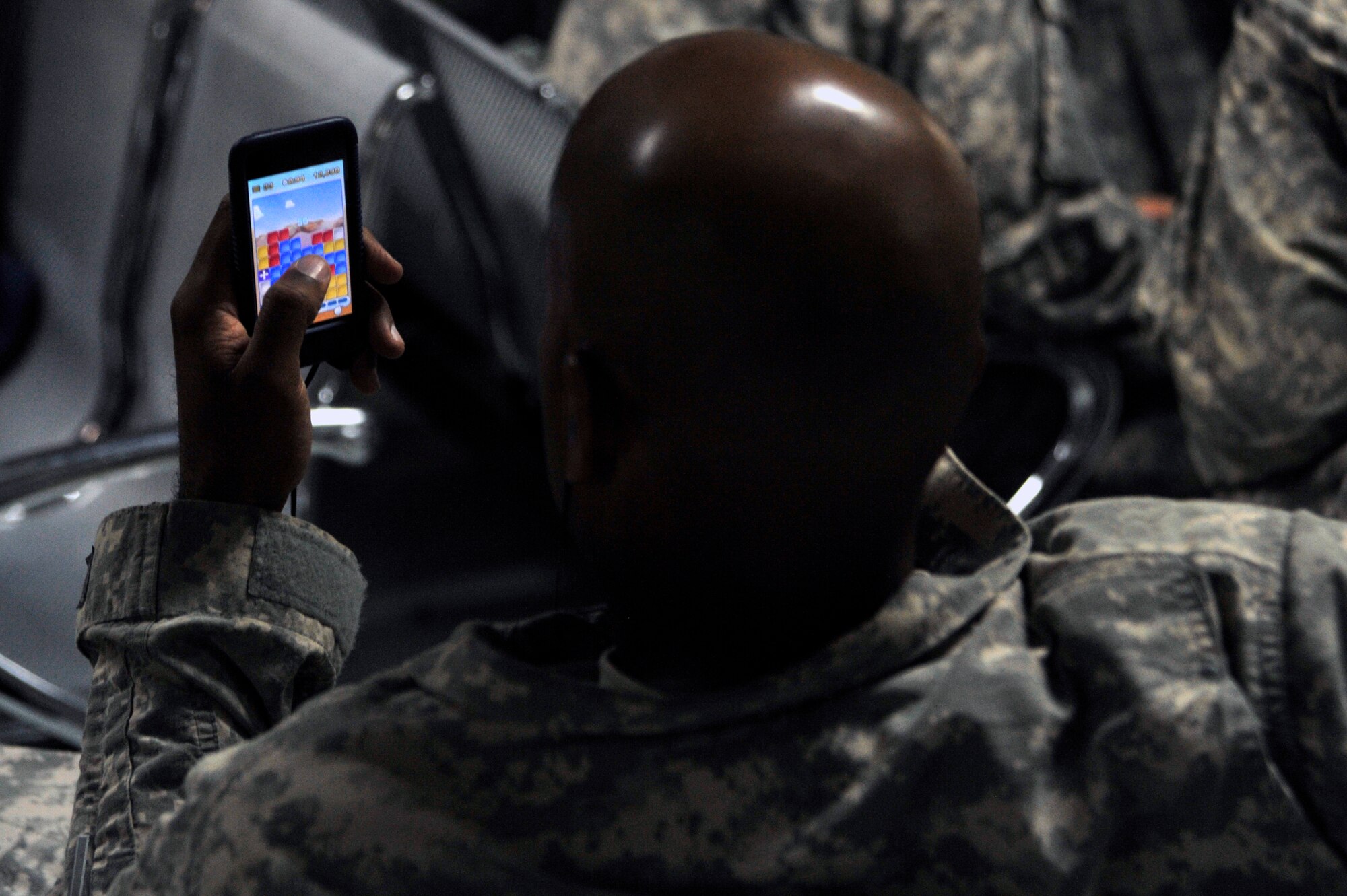 A Soldier from Charlie Company, 67th Expeditionary Signal Battalion, out of Fort Gordon, Ga, passes time by playing games on his cell phone while waiting in the terminal to redeploy July 10, 2010, at Sather Air Base, Iraq. The Charlie Co. redeployment is part of the drawdown to 50,000 troops in Iraq by August 31, 2010. (U.S. Air Force photo by Senior Airman Perry Aston) (Released)