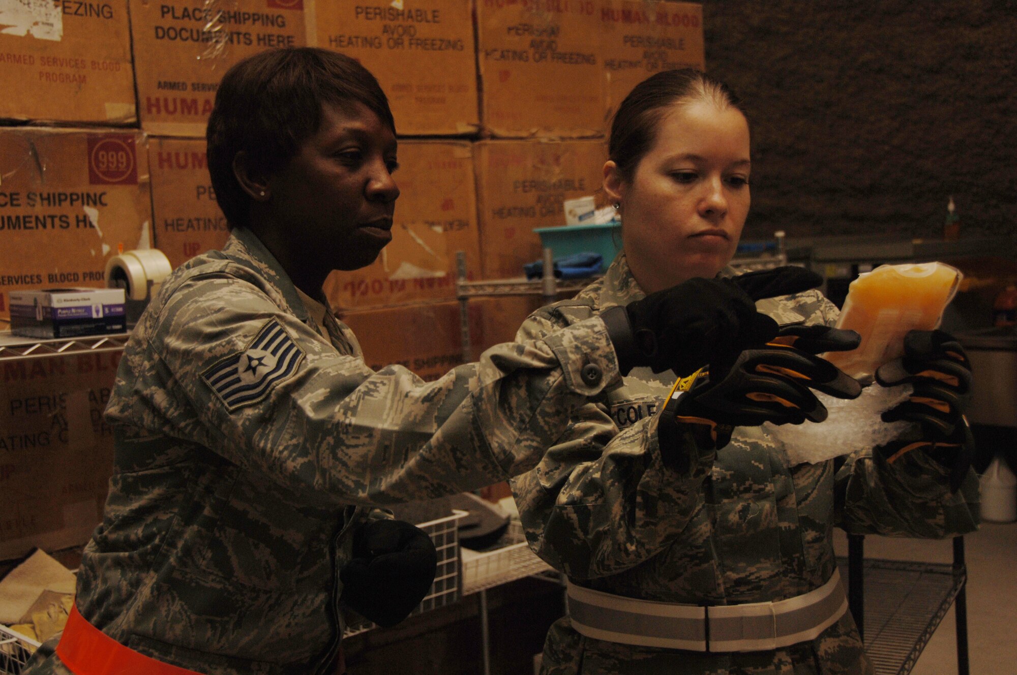 Southwest Asia -- (Left)Tech. Sgt Ramona Tyler and Tech. Sgt. Emily Cole, 379th Medical Group Blood Transshipment Center, check for defects in blood product packaging at an undisclosed location in Southwest Asia July 10. The center distributes blood products used in theater. (U.S. Air Force photo by Tech. Sgt Kimberly Spinner)